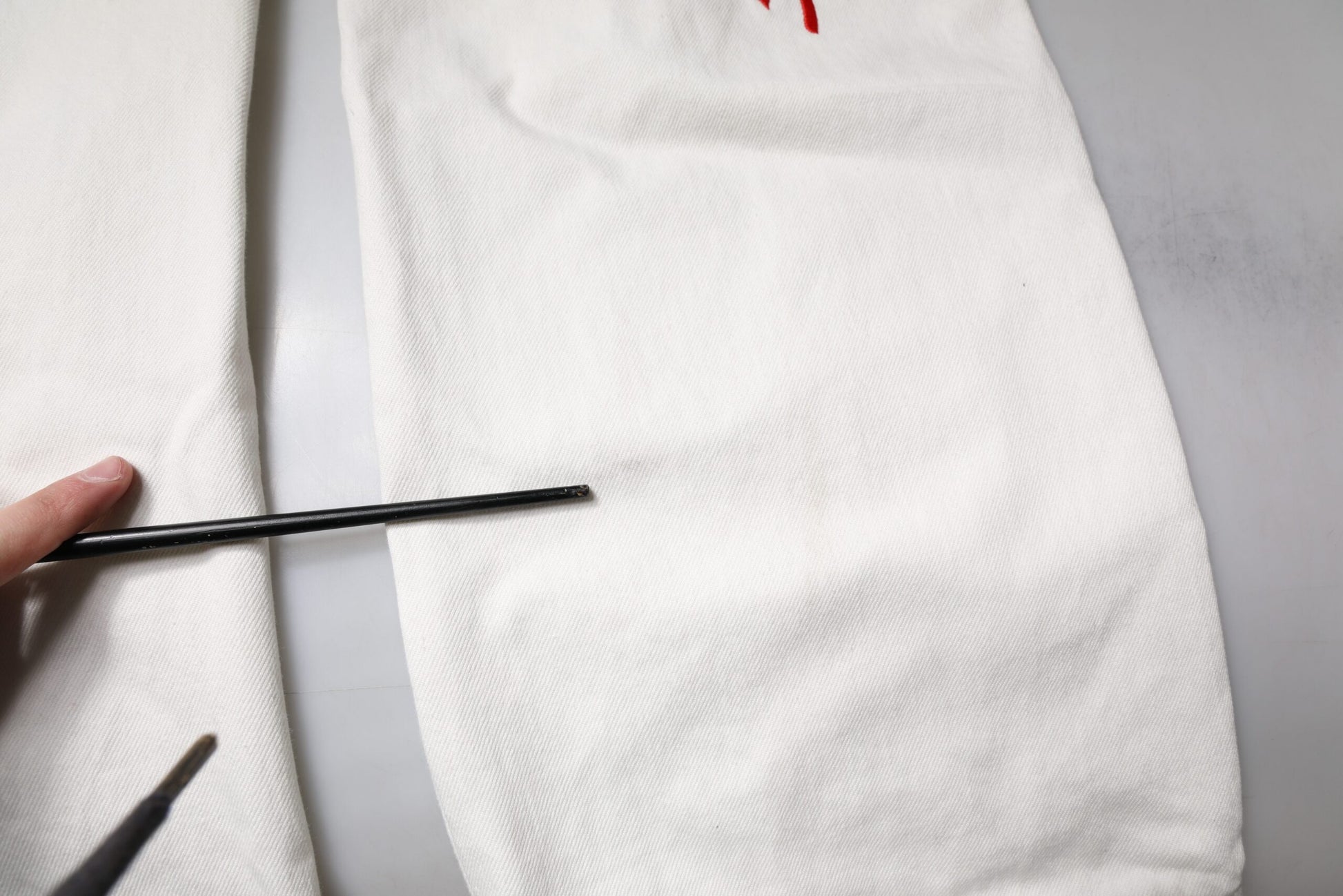 Hand holding a paintbrush over a white cloth on a table