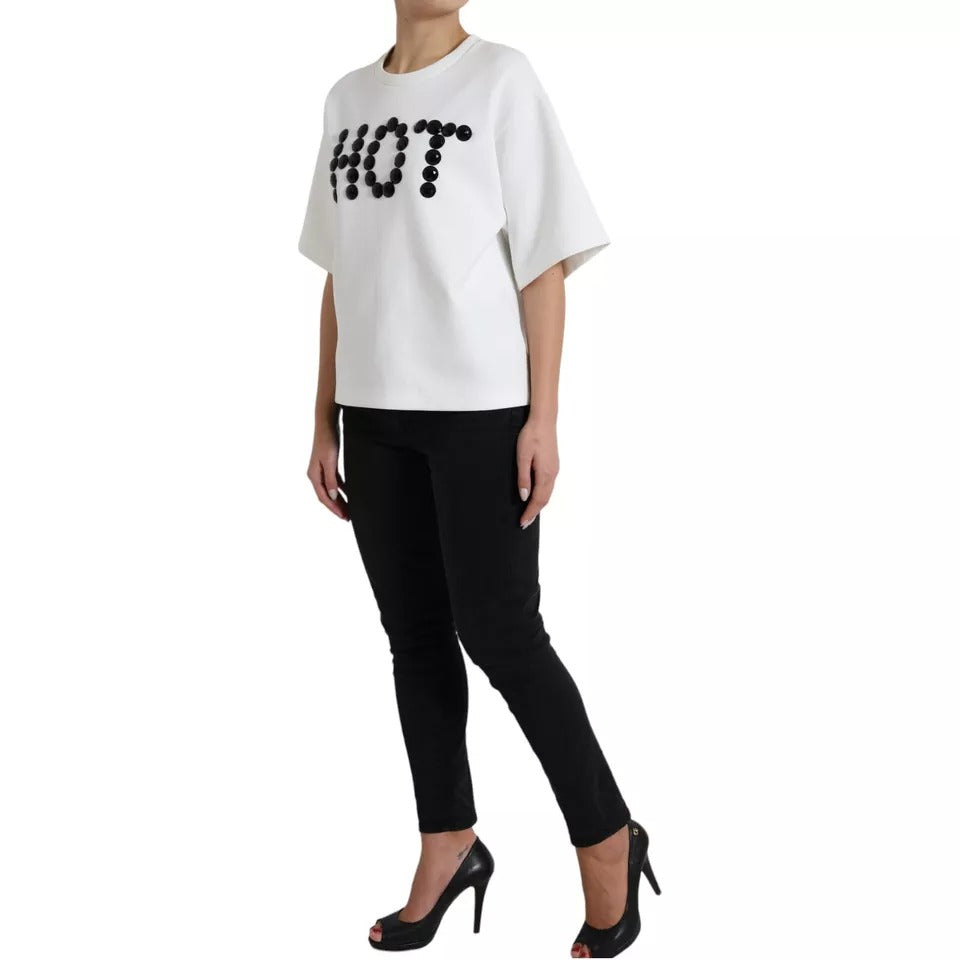 Woman wearing black pants and white sweater with "HOT" written on front
