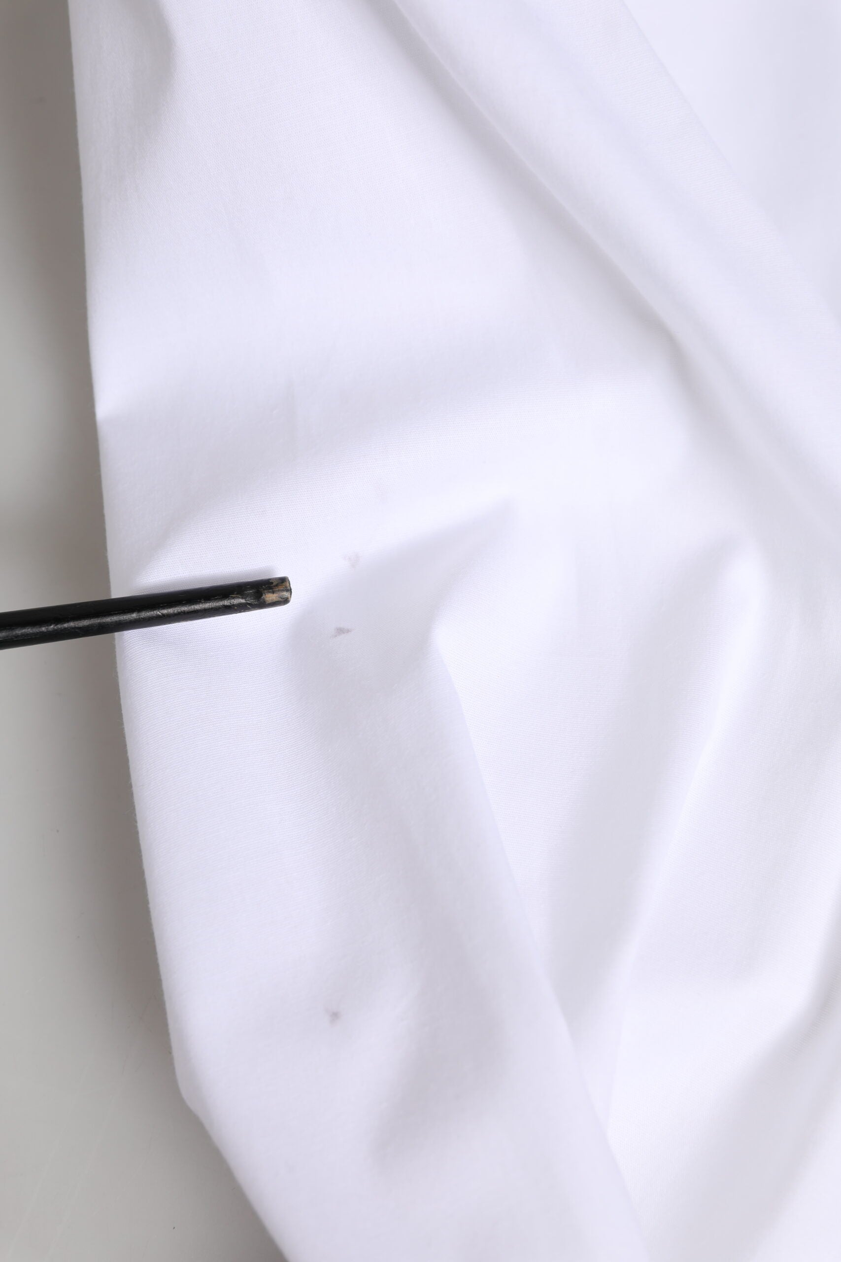 A white cotton collared buttoned dress shirt top with a black pin in the front