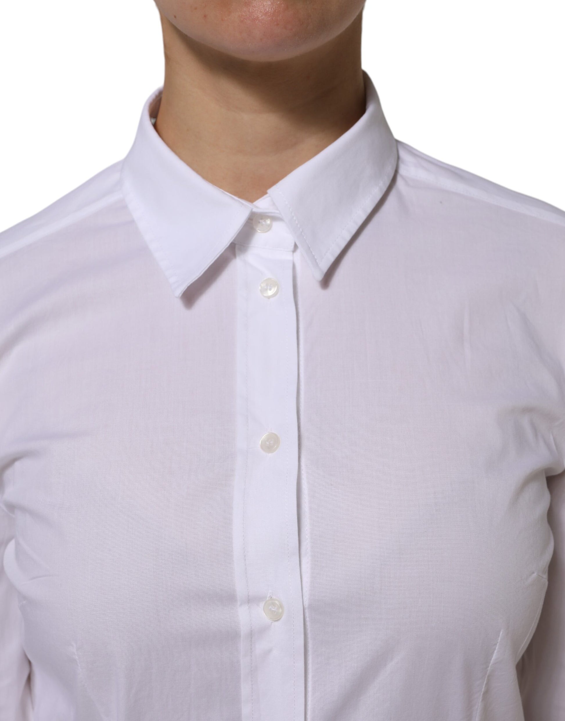 A person wearing a white cotton collared dress shirt with two visible buttons