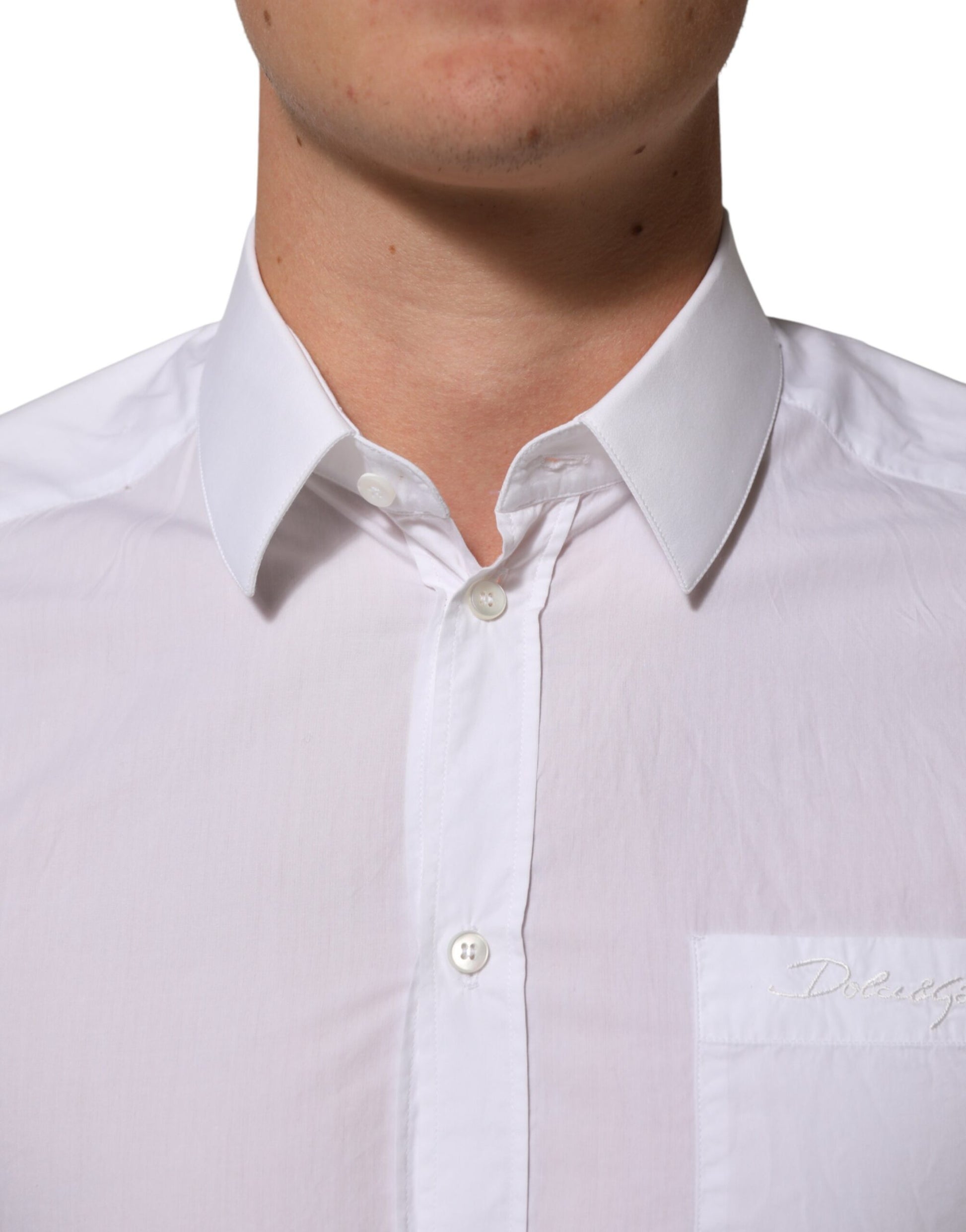 A white collared dress shirt with a gold emblem on the left chest