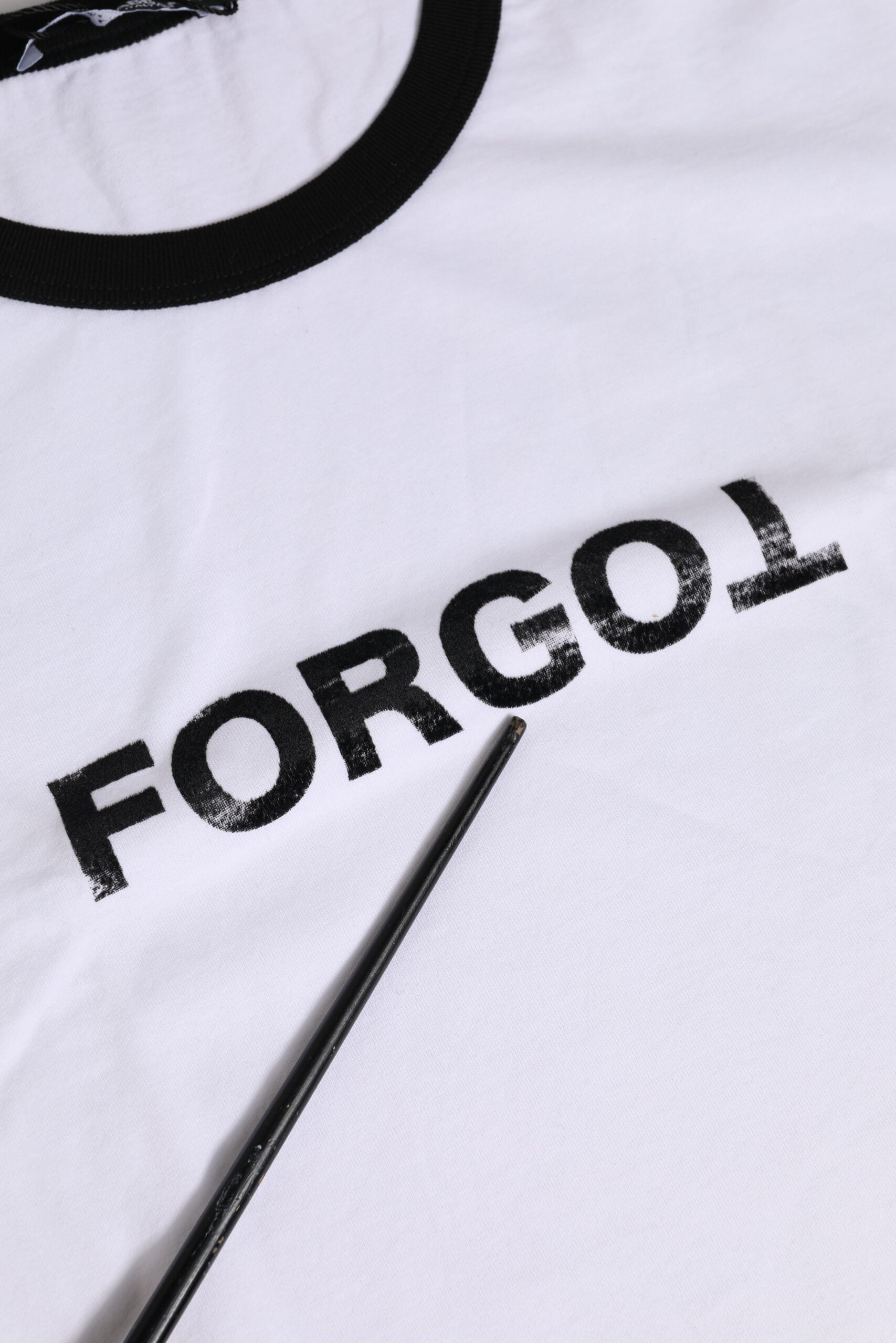 Hand holding a paintbrush over a white fabric with black lettering