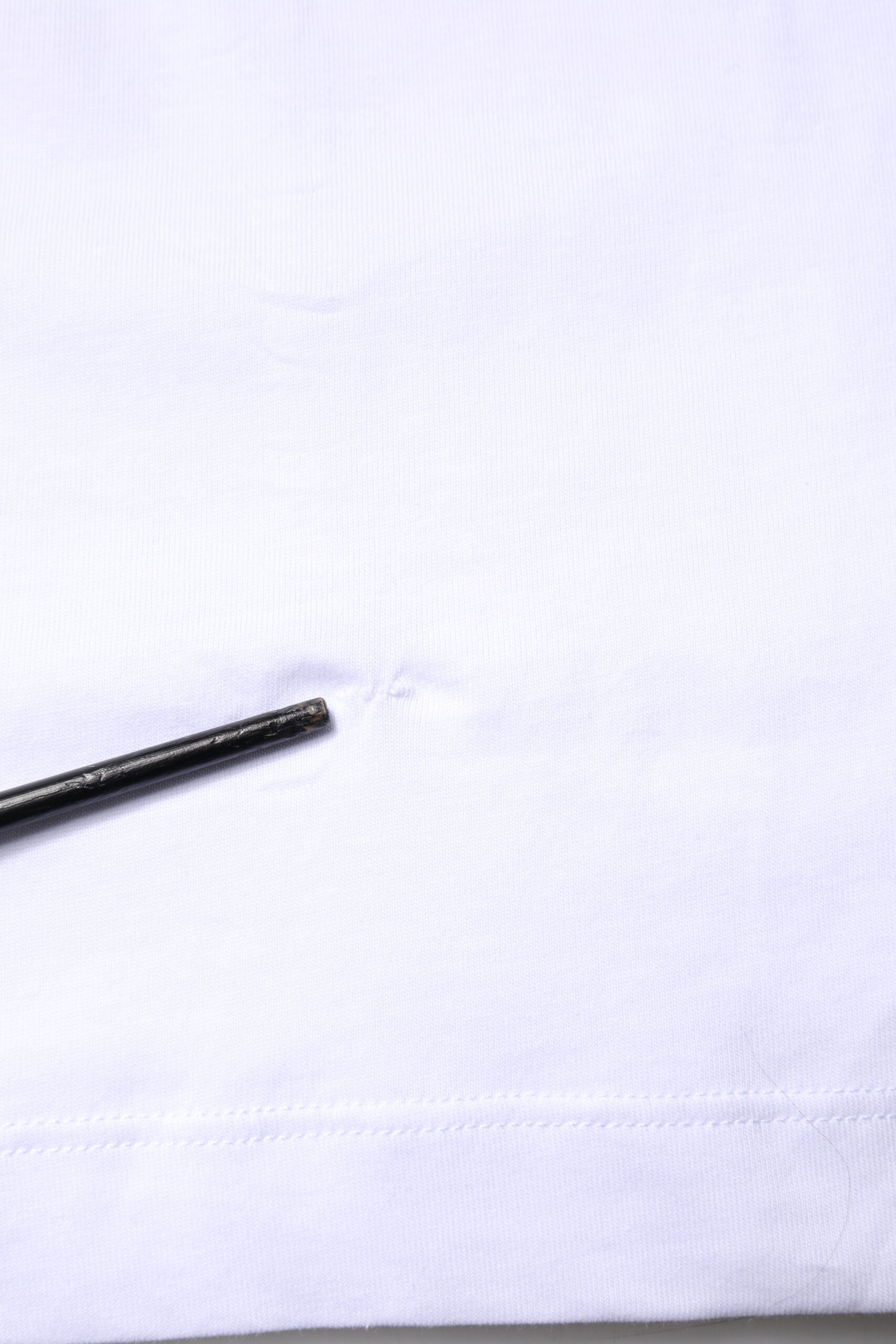 Small black pin on white fabric