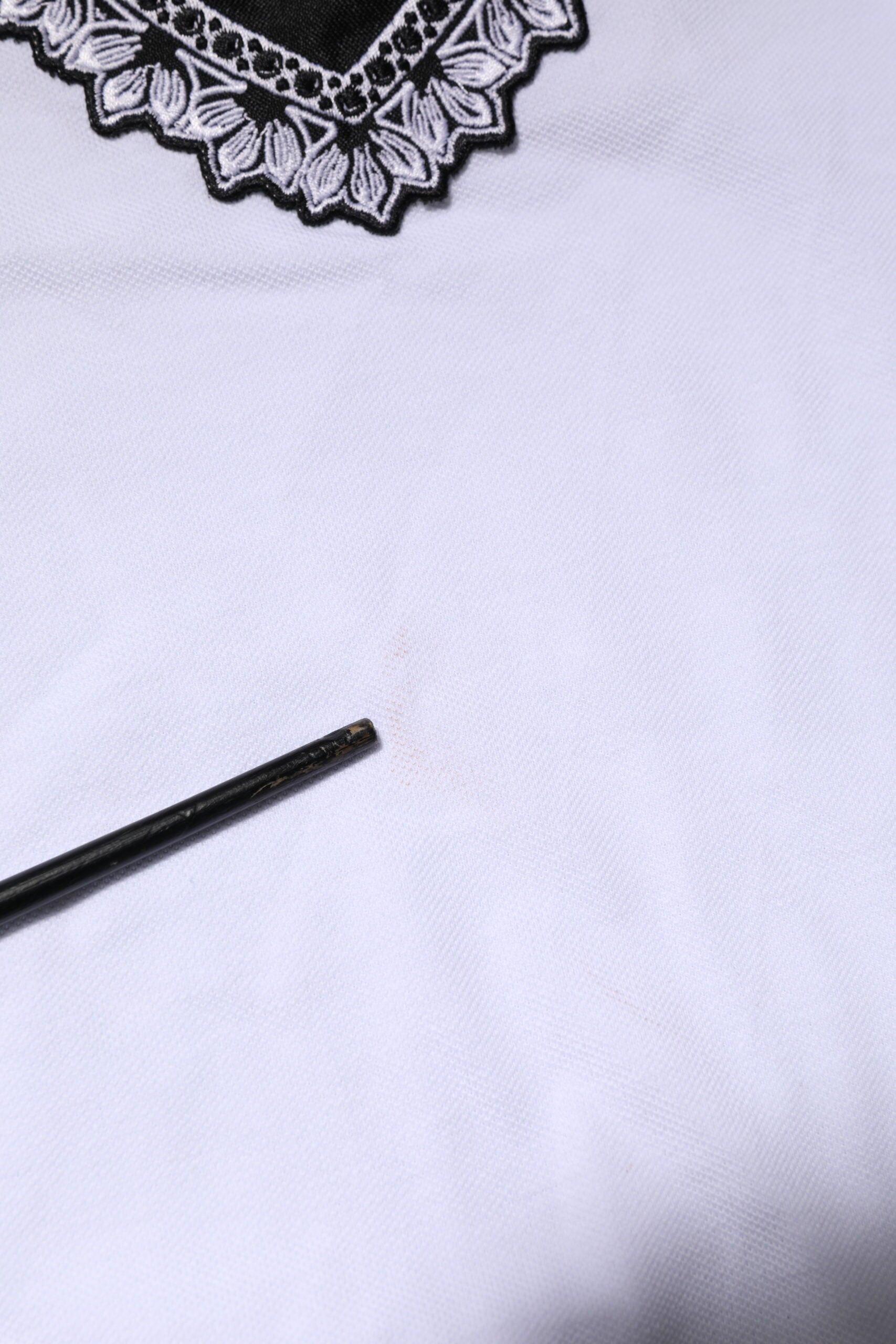 White lace fabric with a small black mark on it