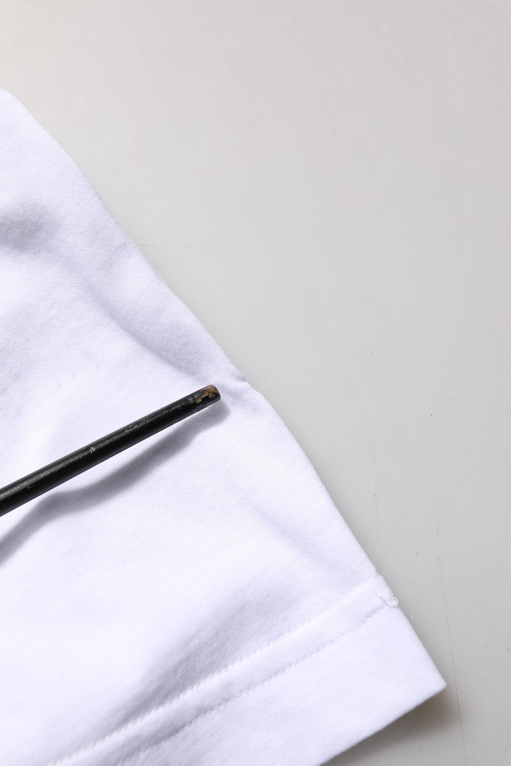 A black sewing needle on a white cotton t-shirt