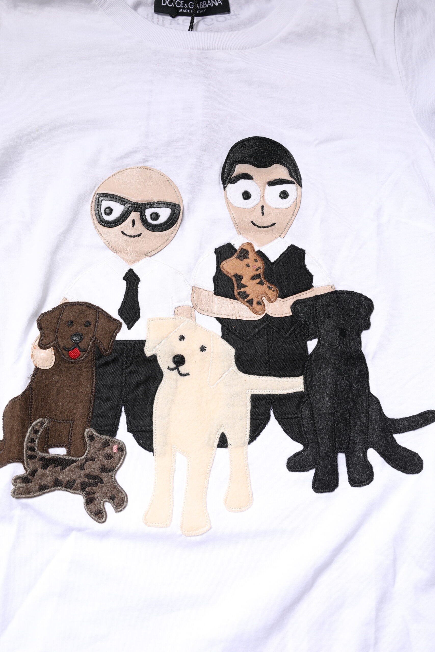 White t-shirt with cartoon illustration of two men sitting on a couch surrounded by dogs
