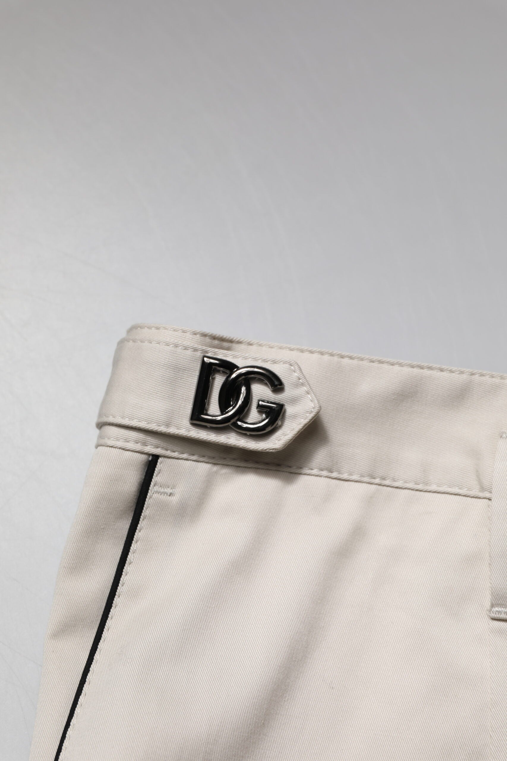 A pair of white cotton dress pants with a slim fit and a logo on the side