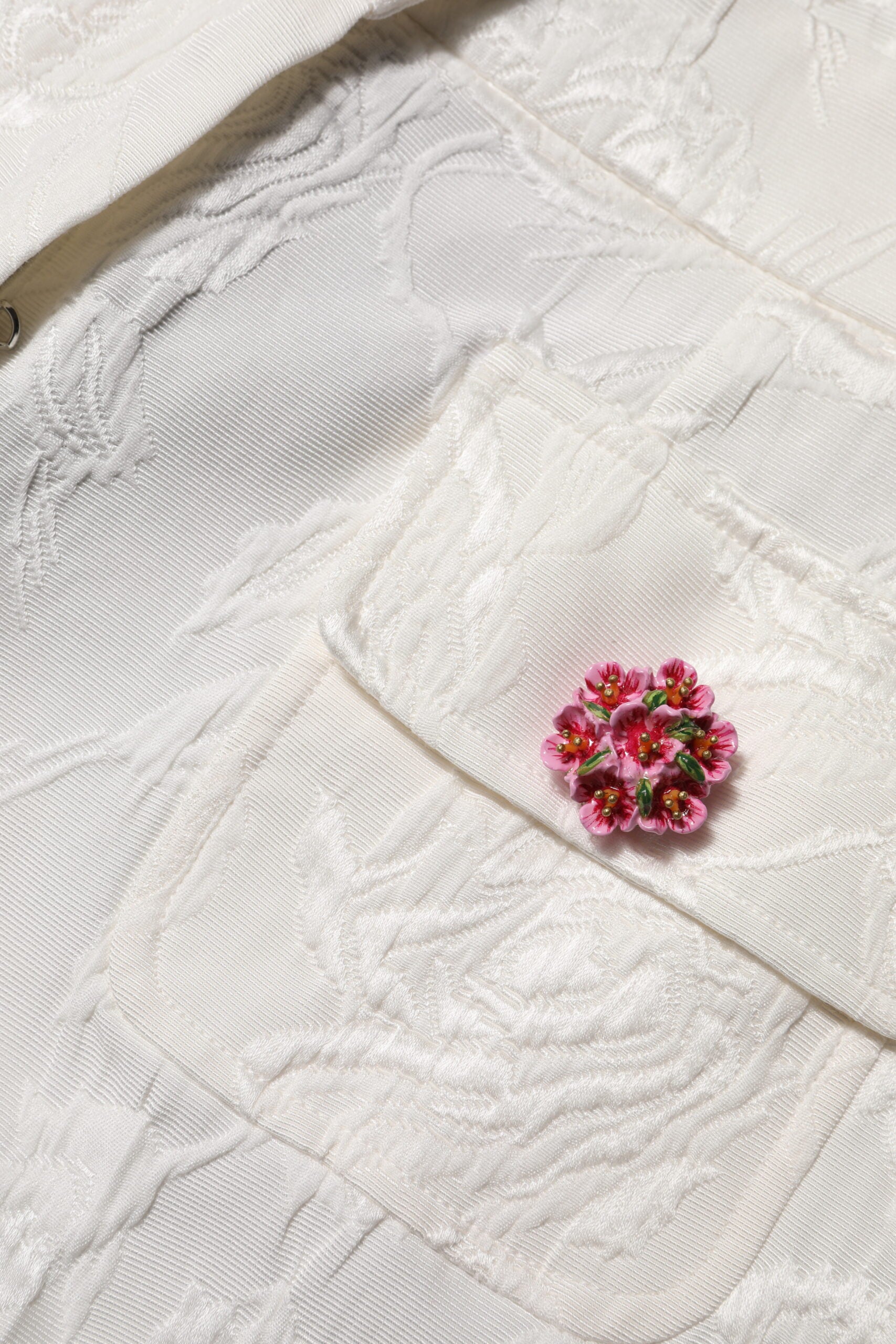 Pink embroidered flower on white fabric