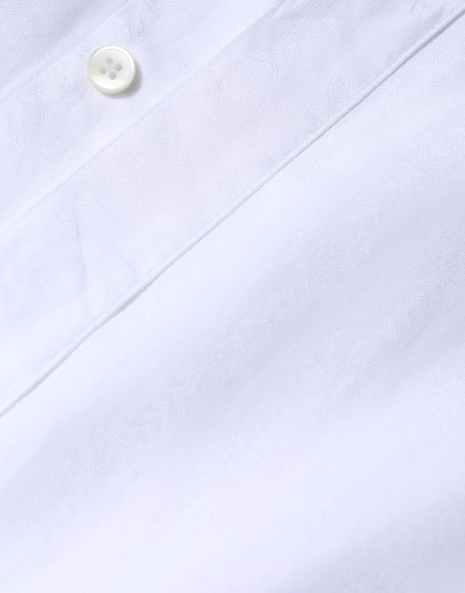 A white cotton formal men's dress shirt with a gold button and a collar