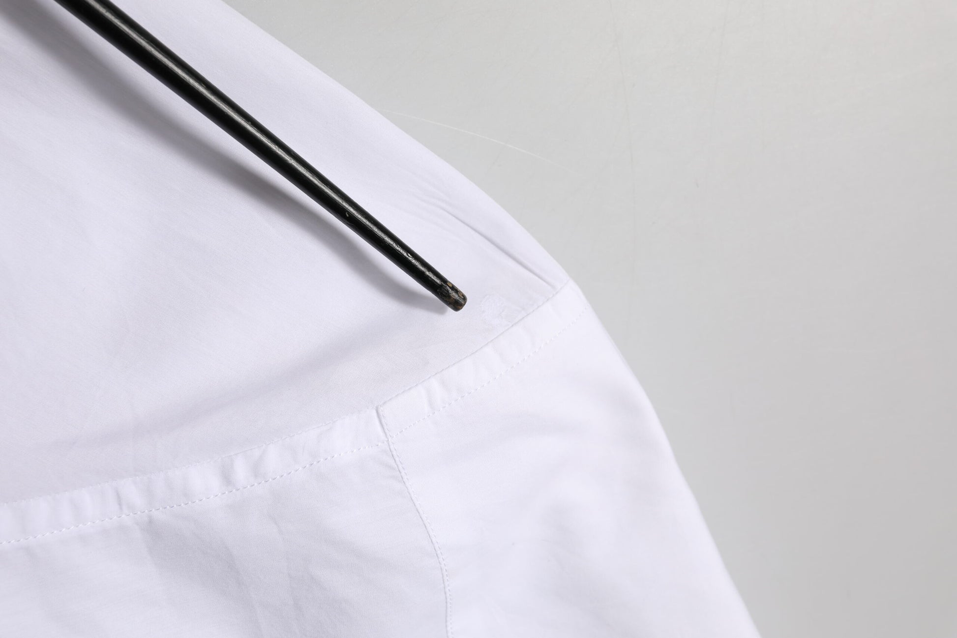 A white cotton dress shirt with a gold patch on the left chest
