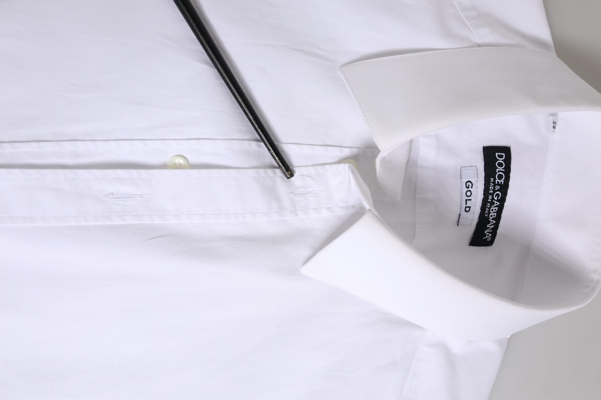 A white cotton dress shirt with long sleeves, featuring a gold label