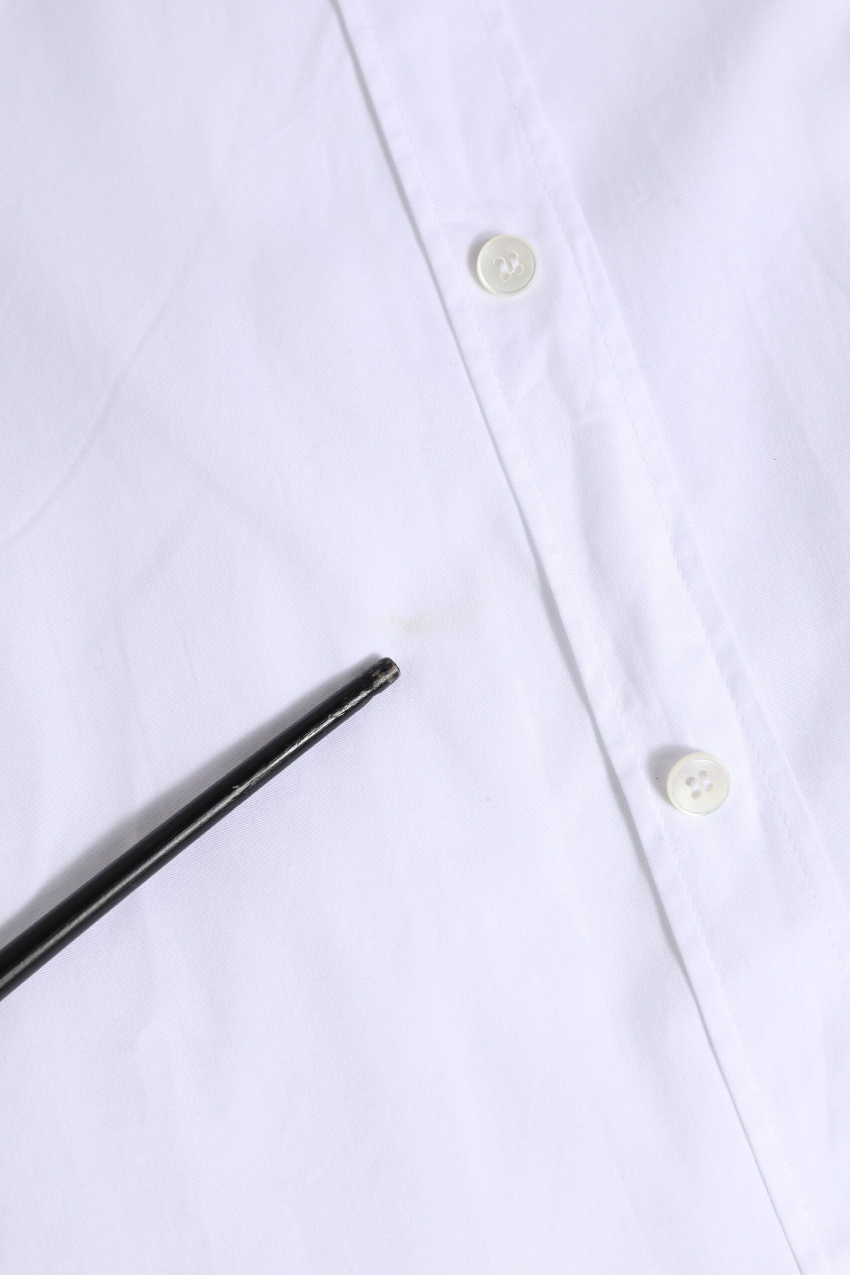 A white cotton dress shirt with gold buttons and a black tie