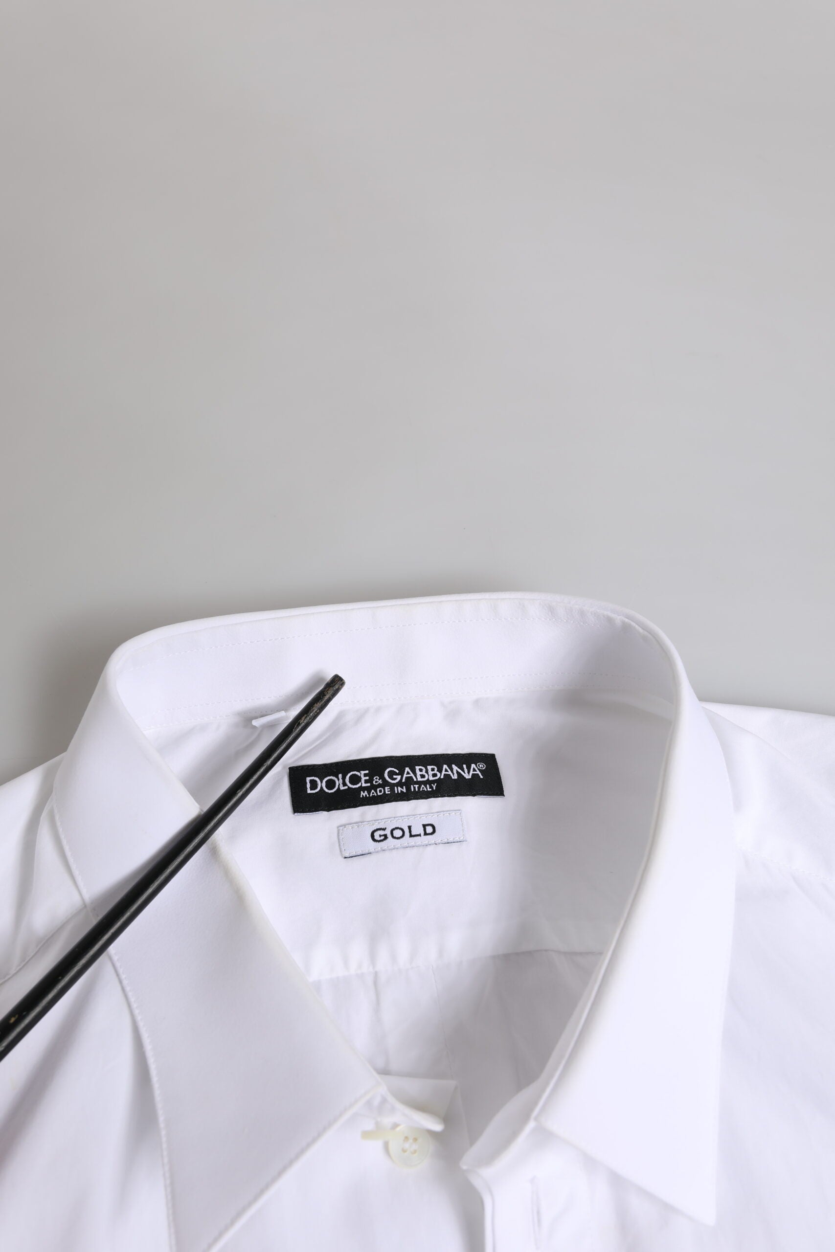 A white cotton dress shirt with long sleeves, featuring a gold label