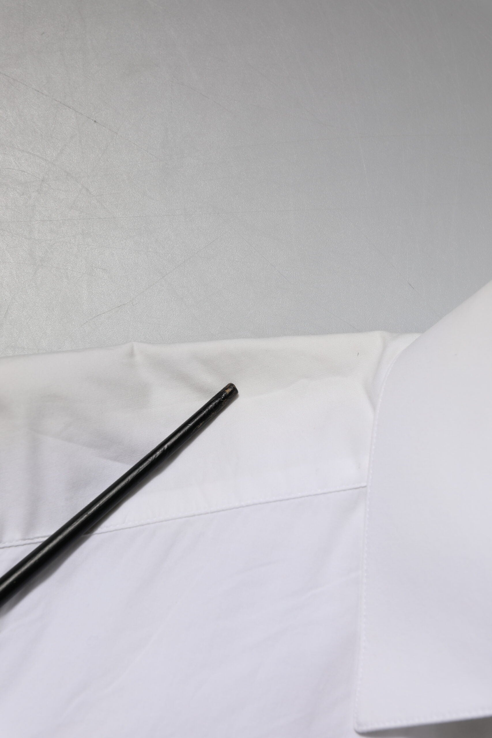 A white cotton dress shirt with long sleeves, featuring a gold design