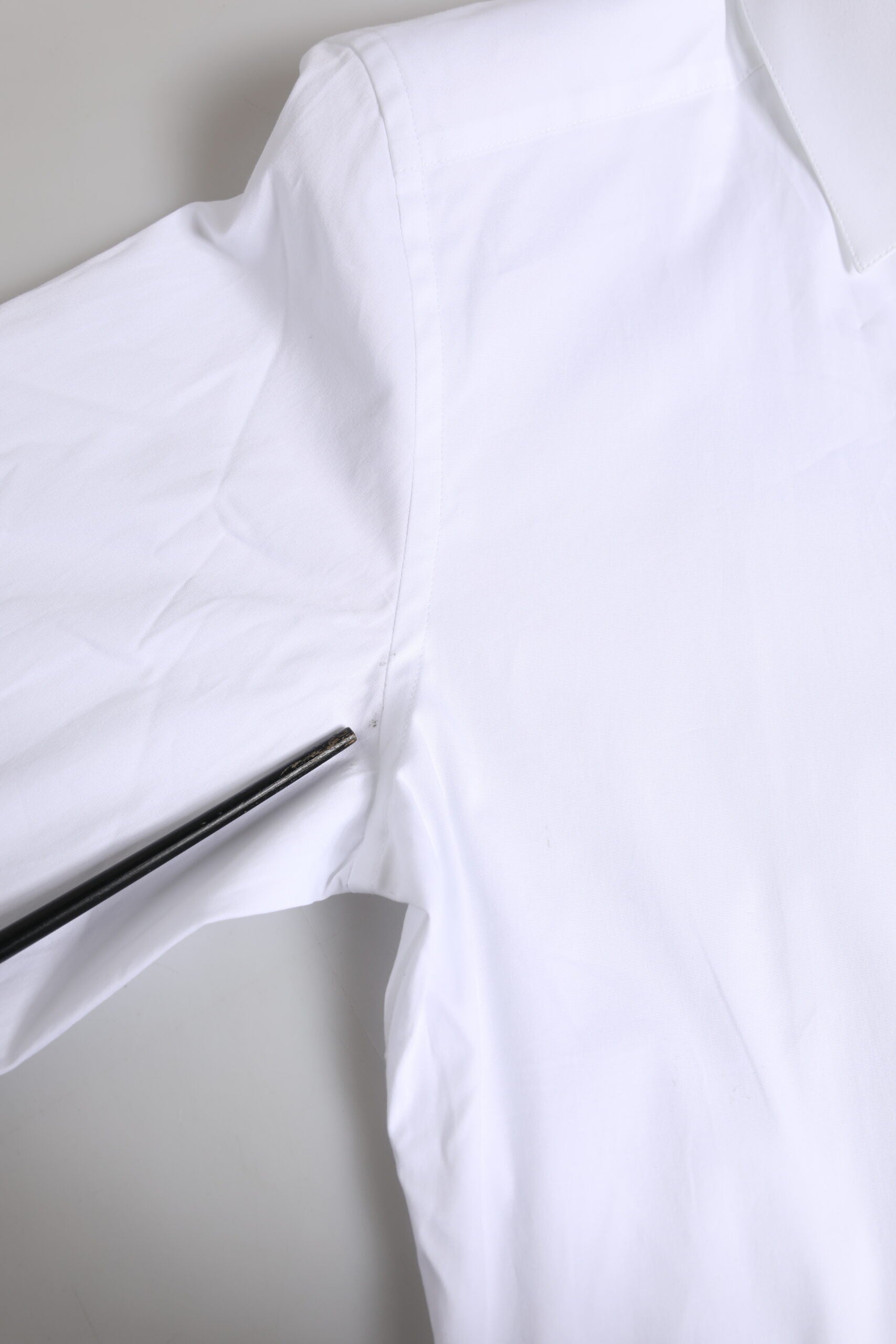 A white cotton dress shirt with long sleeves, featuring a gold design