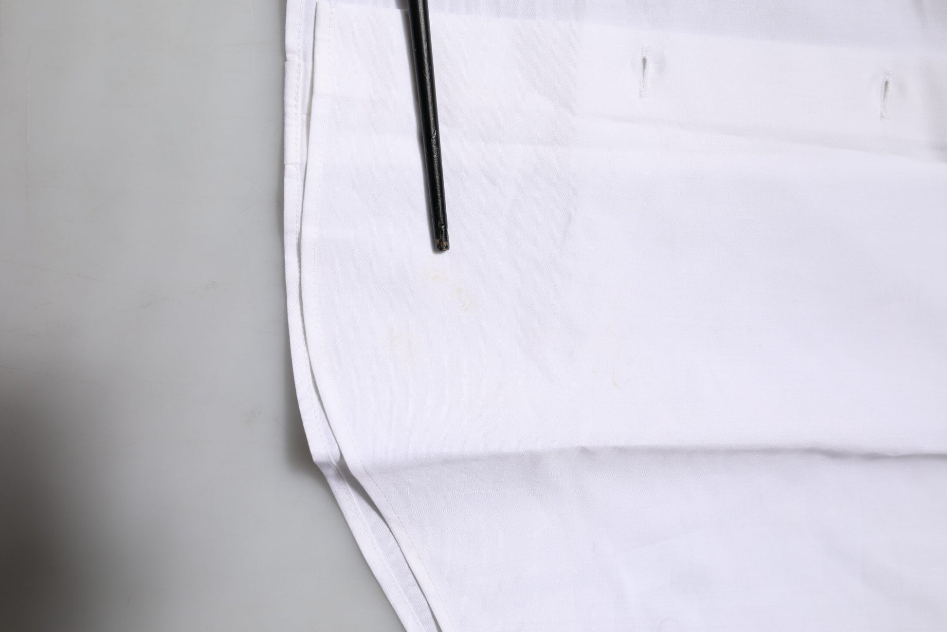 A white cotton dress shirt with long sleeves and a gold button