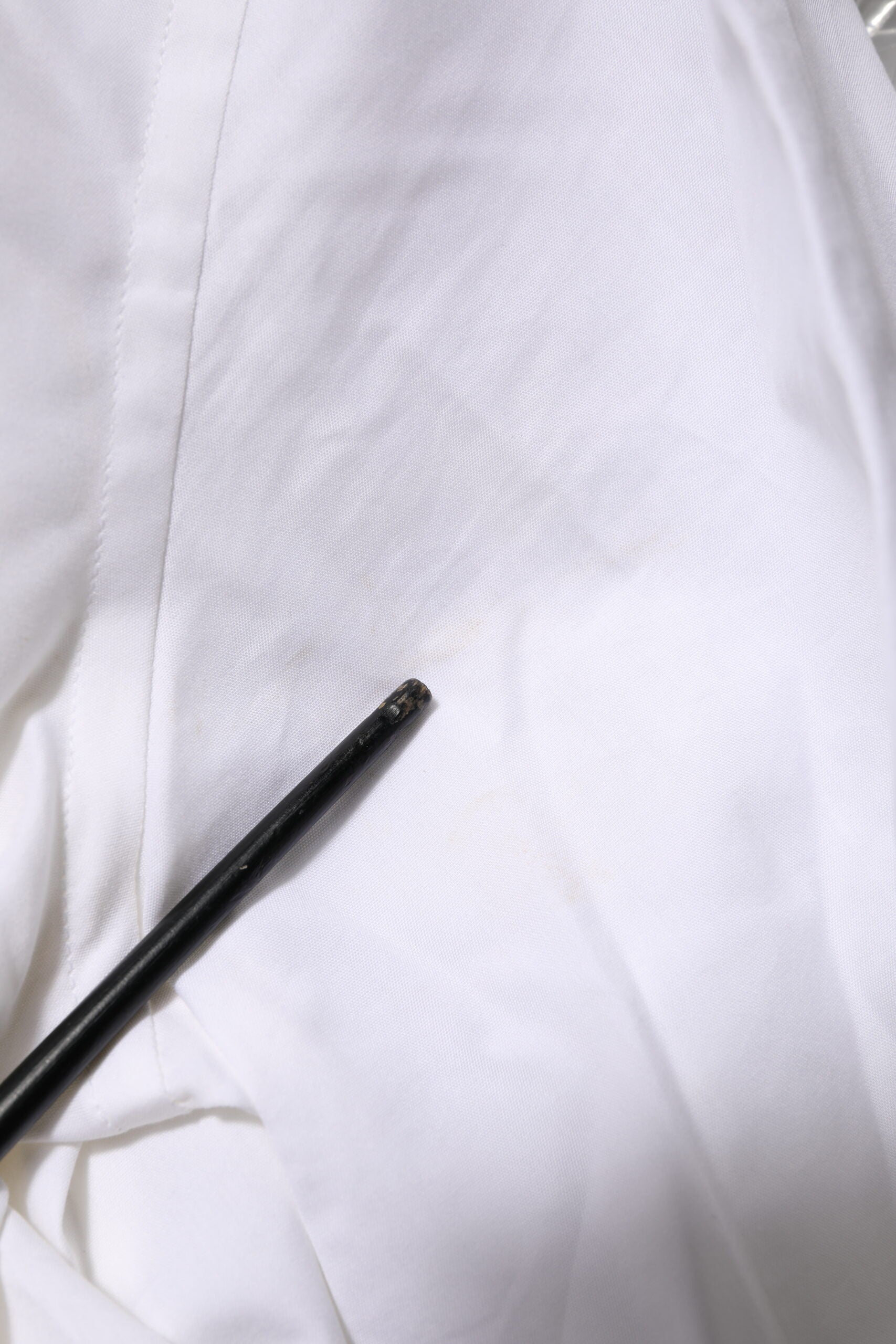 A white cotton dress shirt with long sleeves and a gold accent