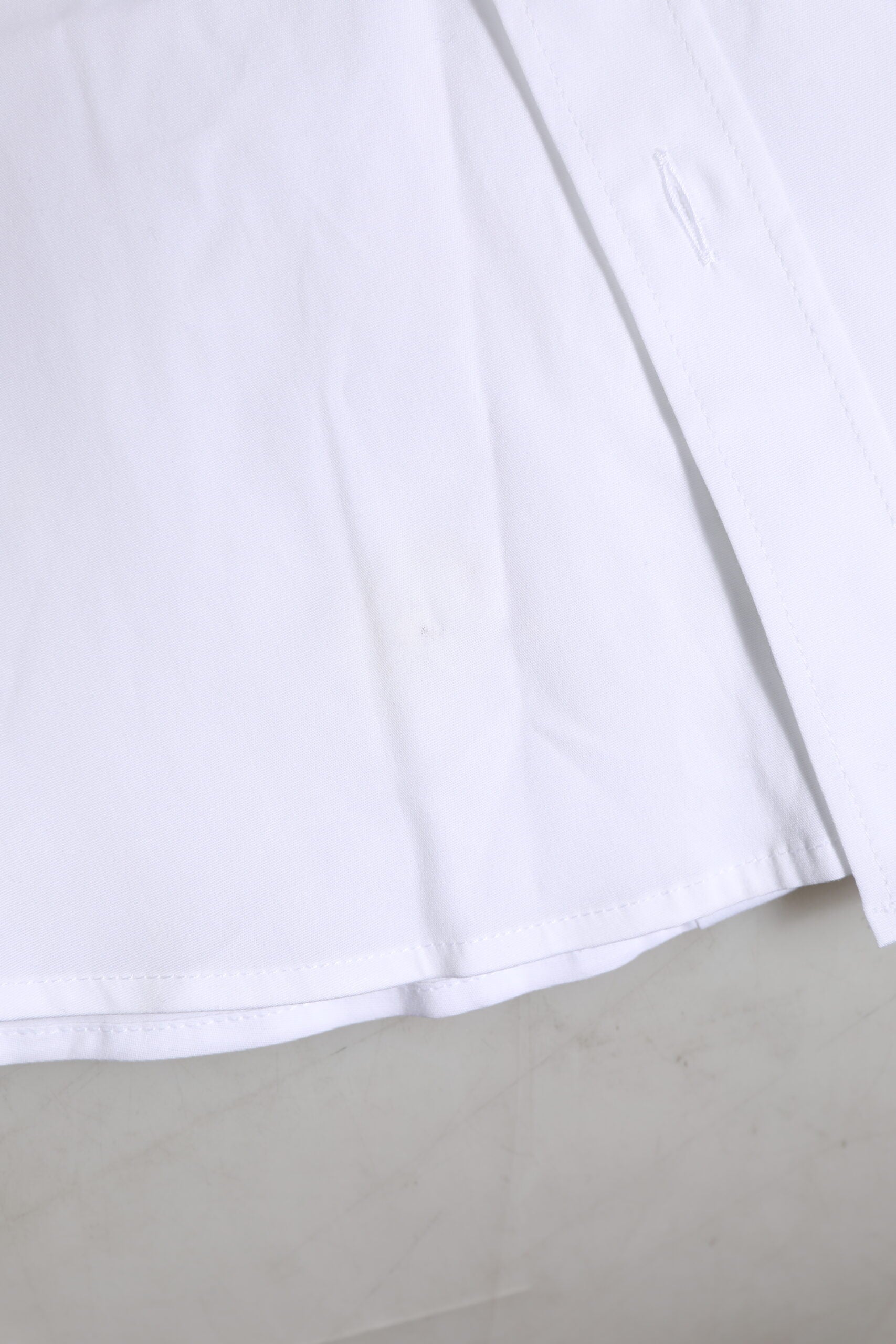 A white cotton dress shirt with long sleeves and gold accents