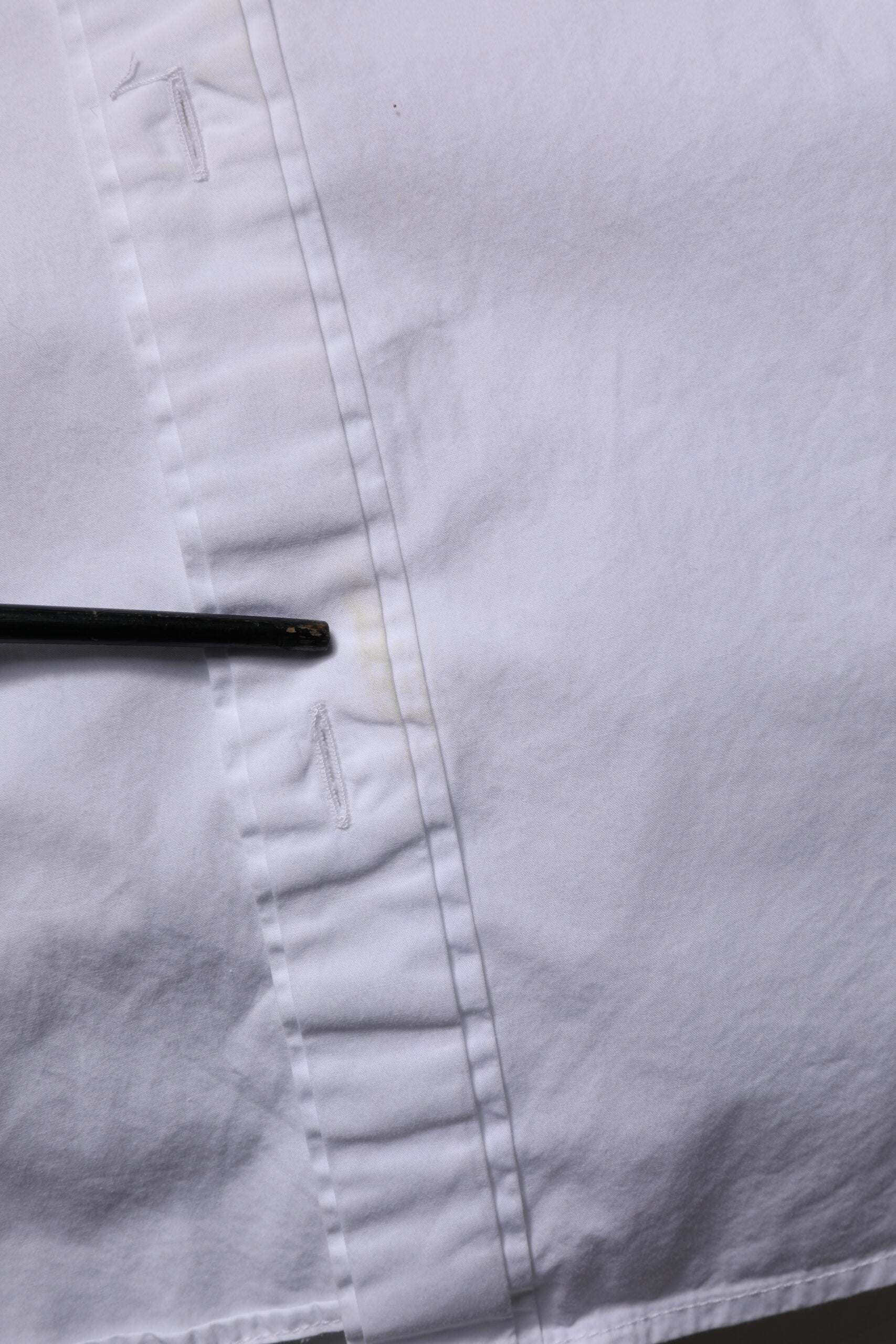 A white cotton dress shirt with long sleeves and gold accents