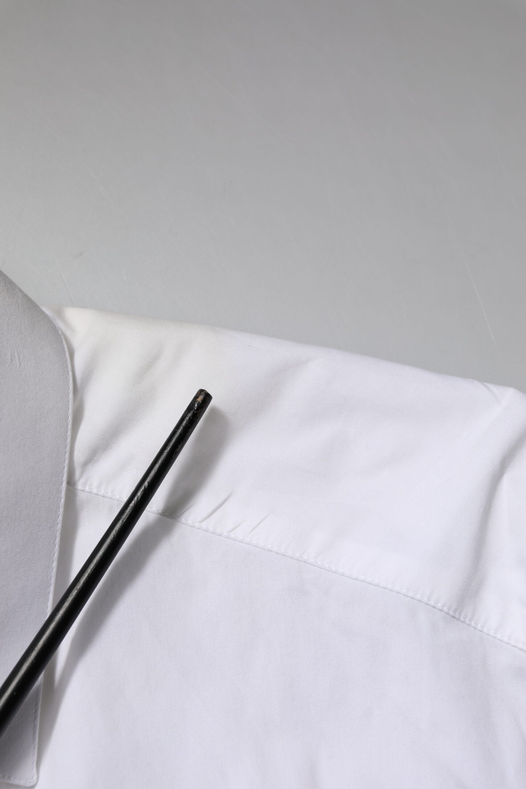 A white cotton dress shirt with long sleeves and gold accents