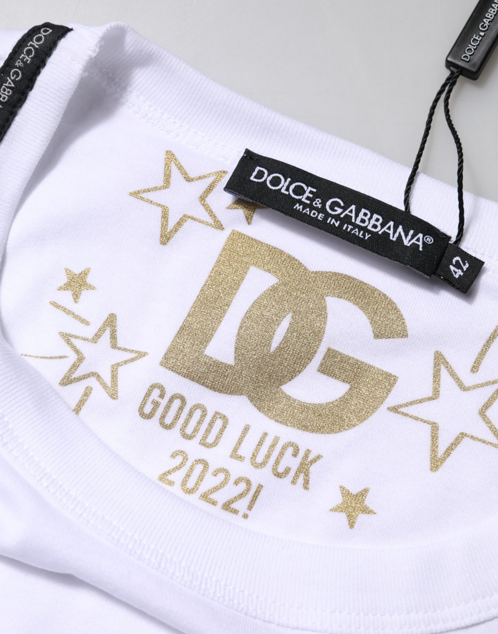 White t-shirt with gold lettering and stars