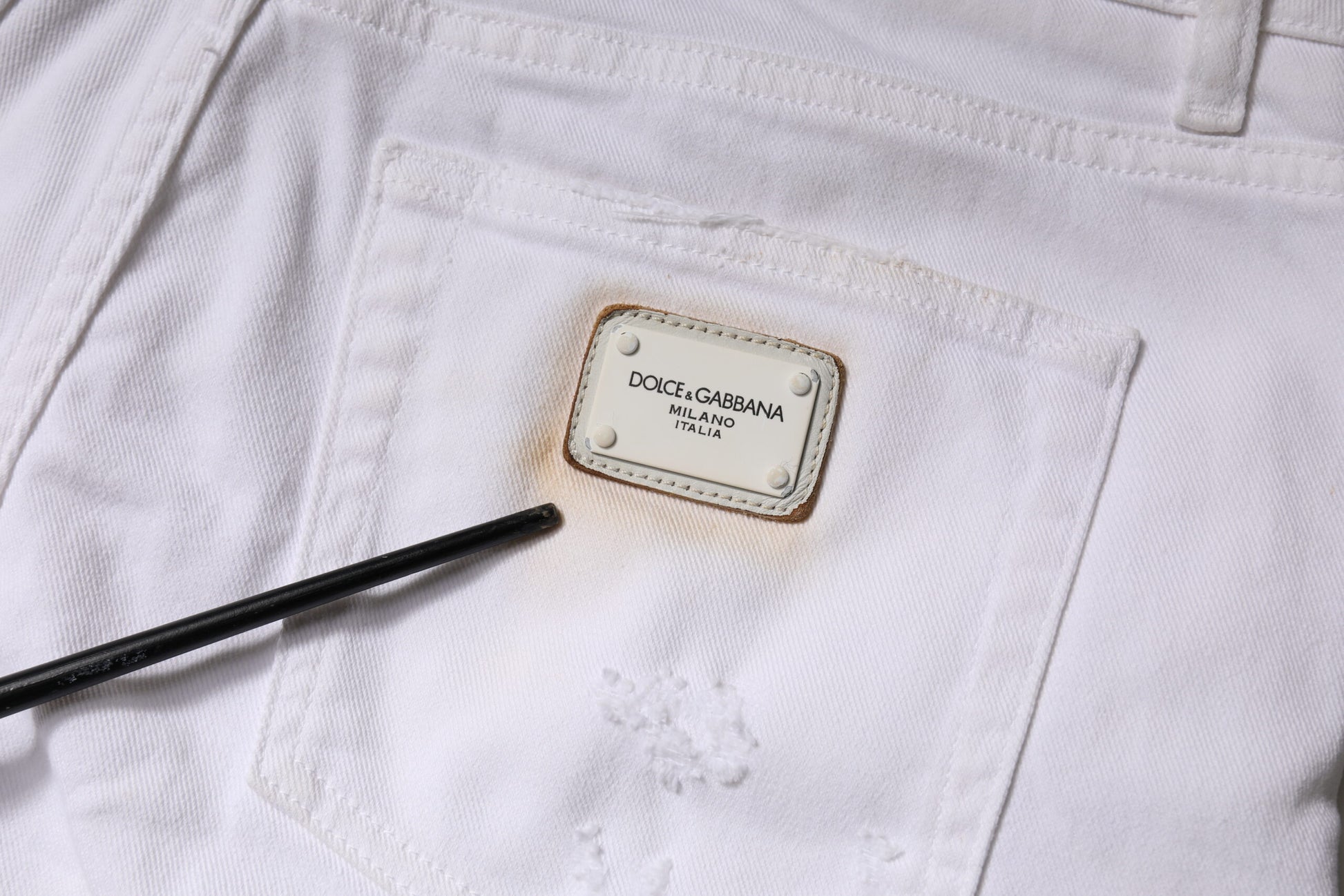 White pants with a brand label on the front pocket