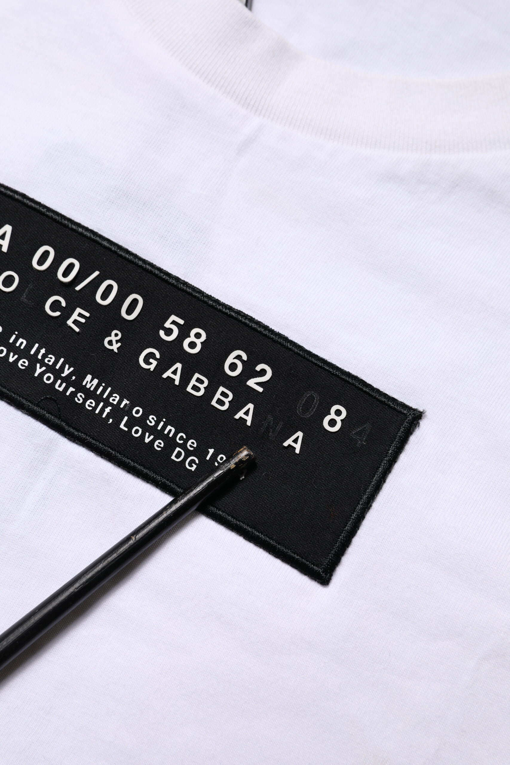 White t-shirt with black label featuring numbers and letters