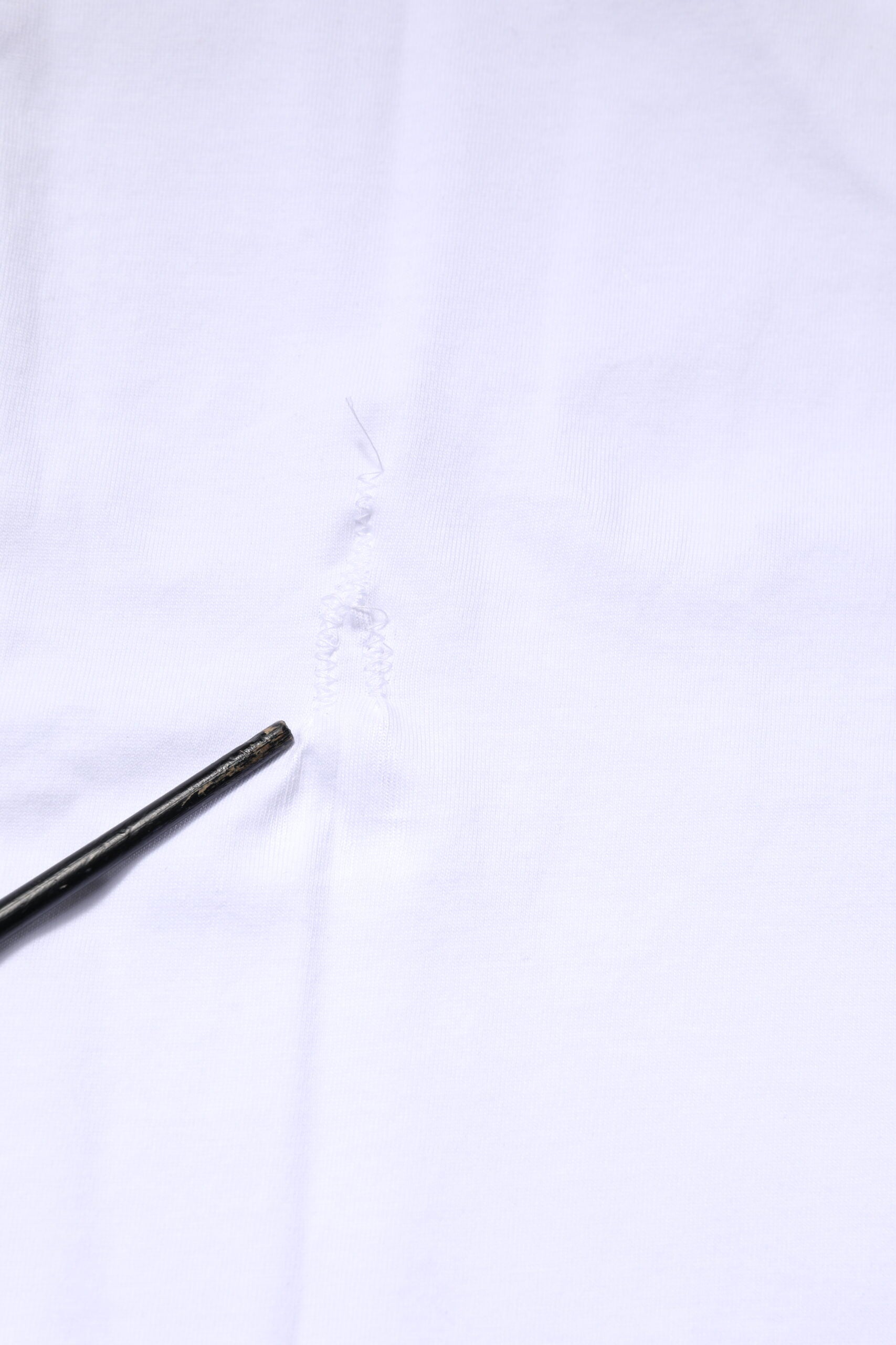 Black sewing needle on white fabric