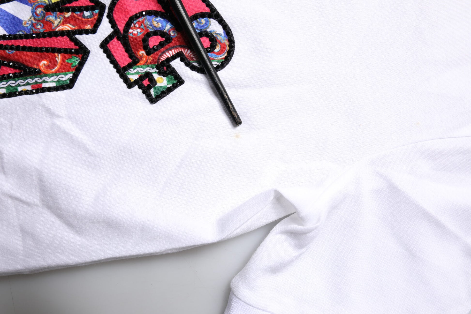 White cloth with embroidered design and black pen lying on top