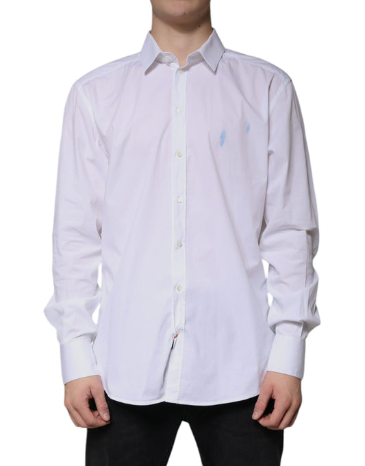 A long sleeved white cotton dress shirt with a gold emblem on the left chest