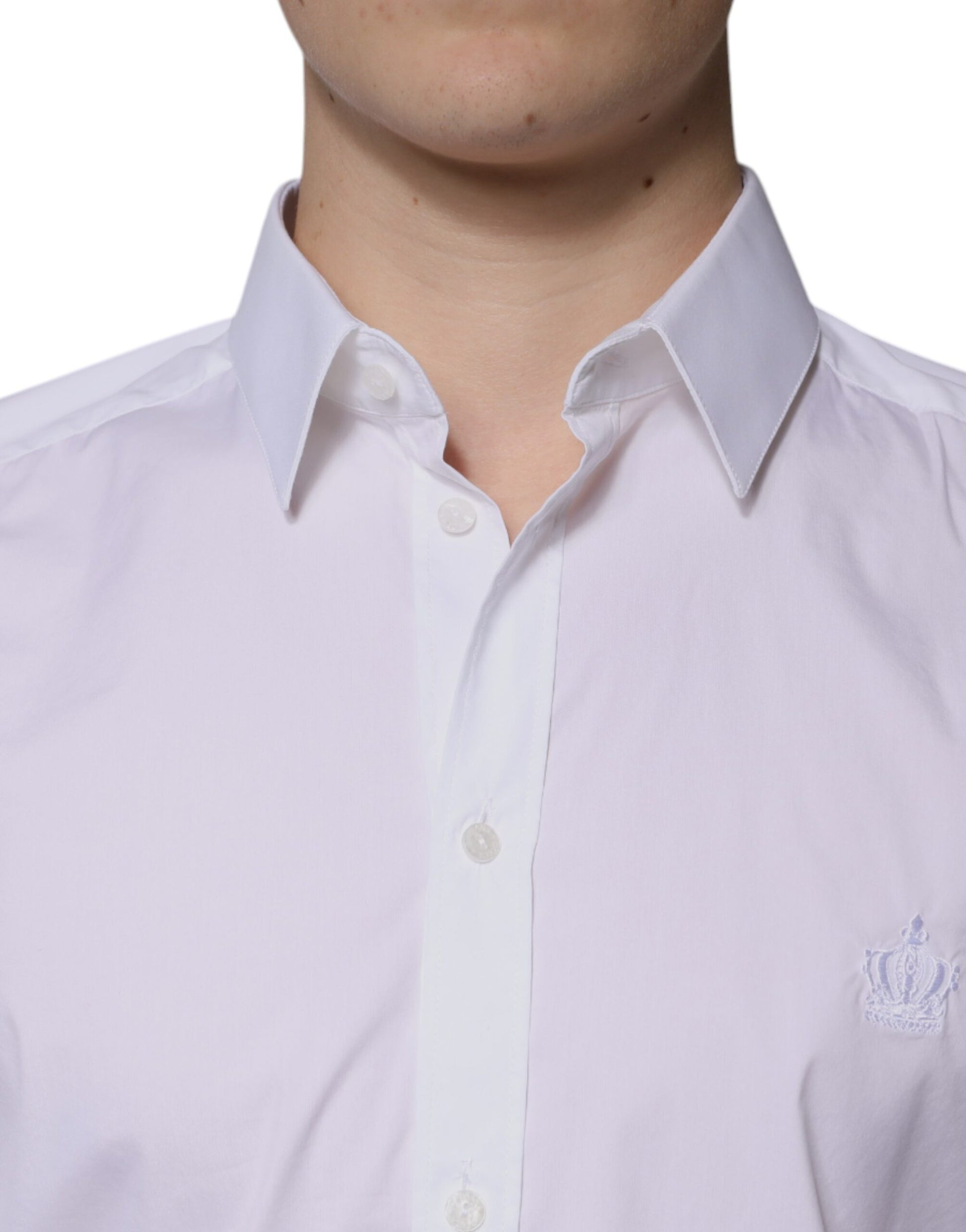 A long sleeved white cotton dress shirt with a gold emblem on the left chest