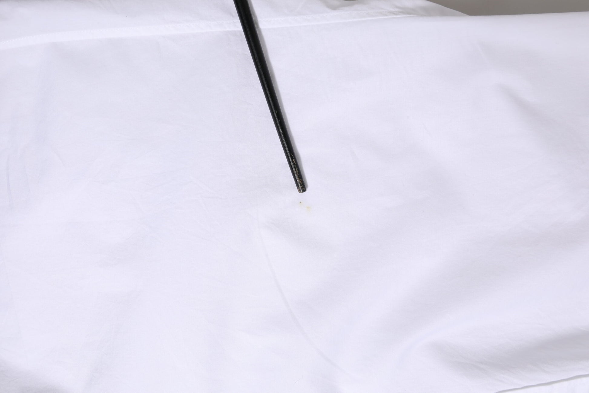 A white cotton long sleeve dress shirt with a black pen mark on it