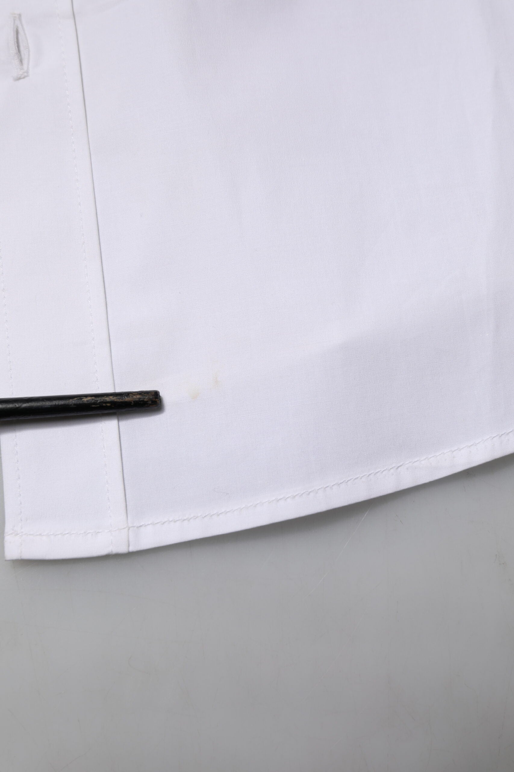 A white cotton long sleeve dress shirt with a black button and collar