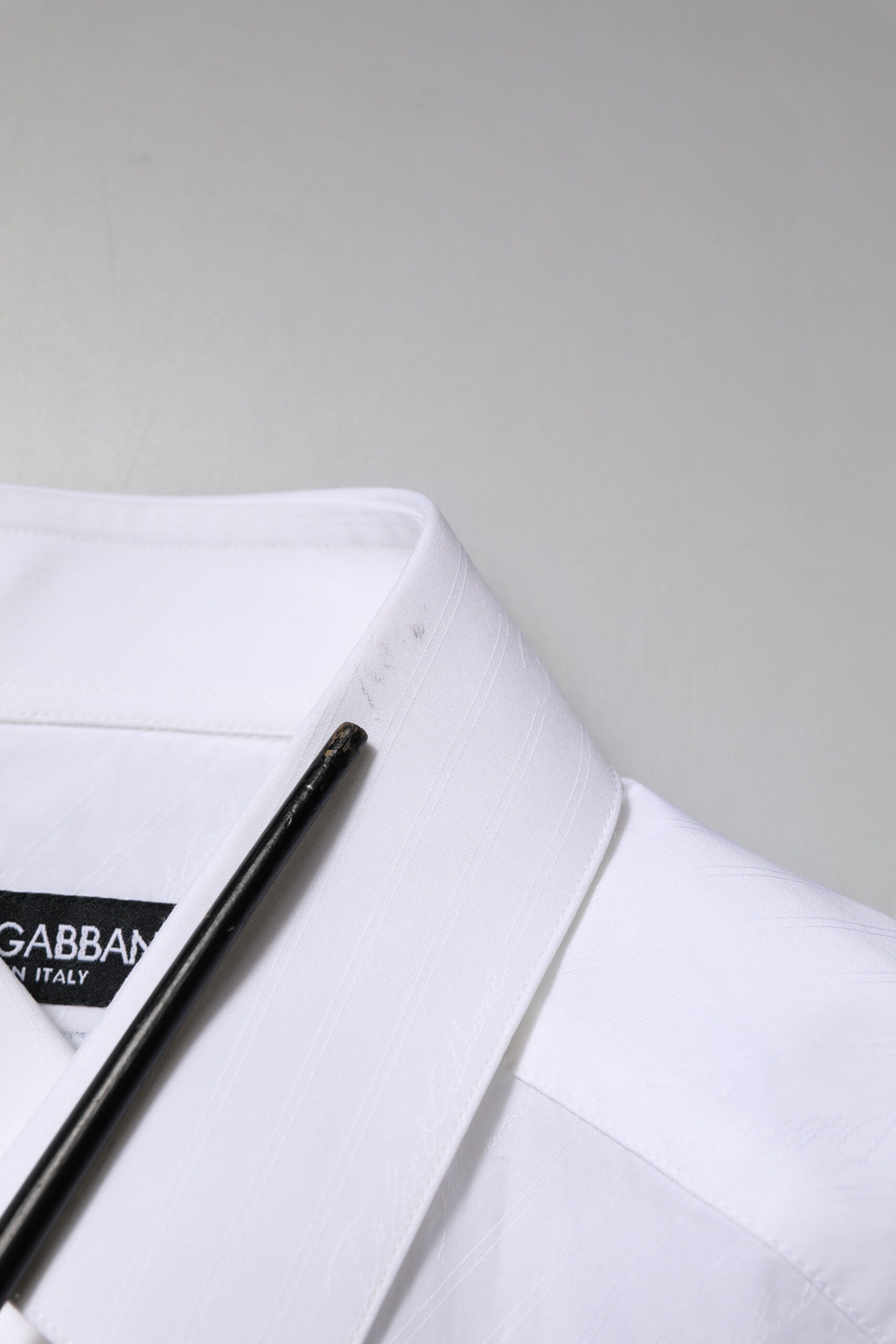 A white cotton dress shirt with a black tie and pen resting on it