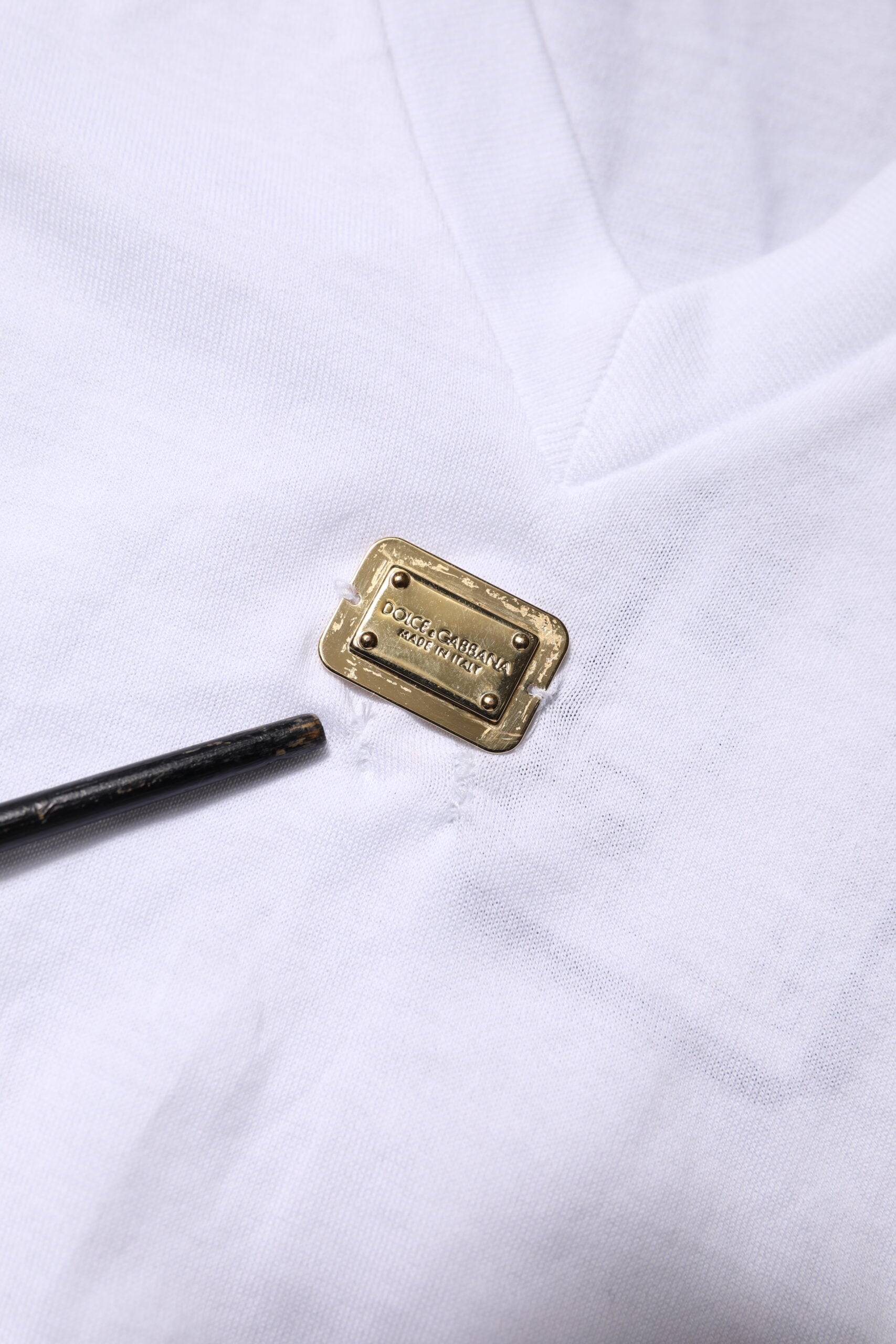Small gold metal button on white fabric