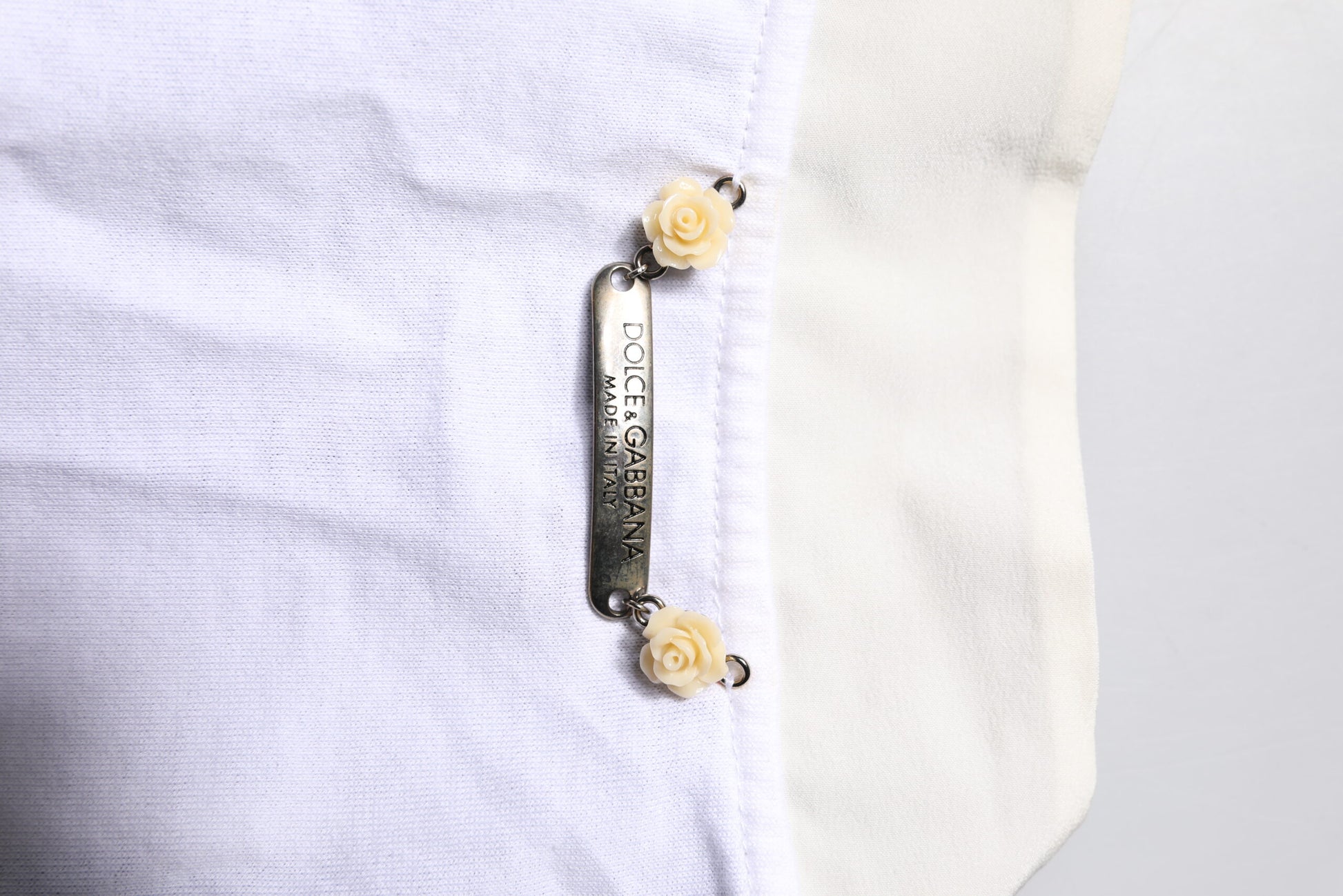 White shirt with a gold button featuring a small flower design