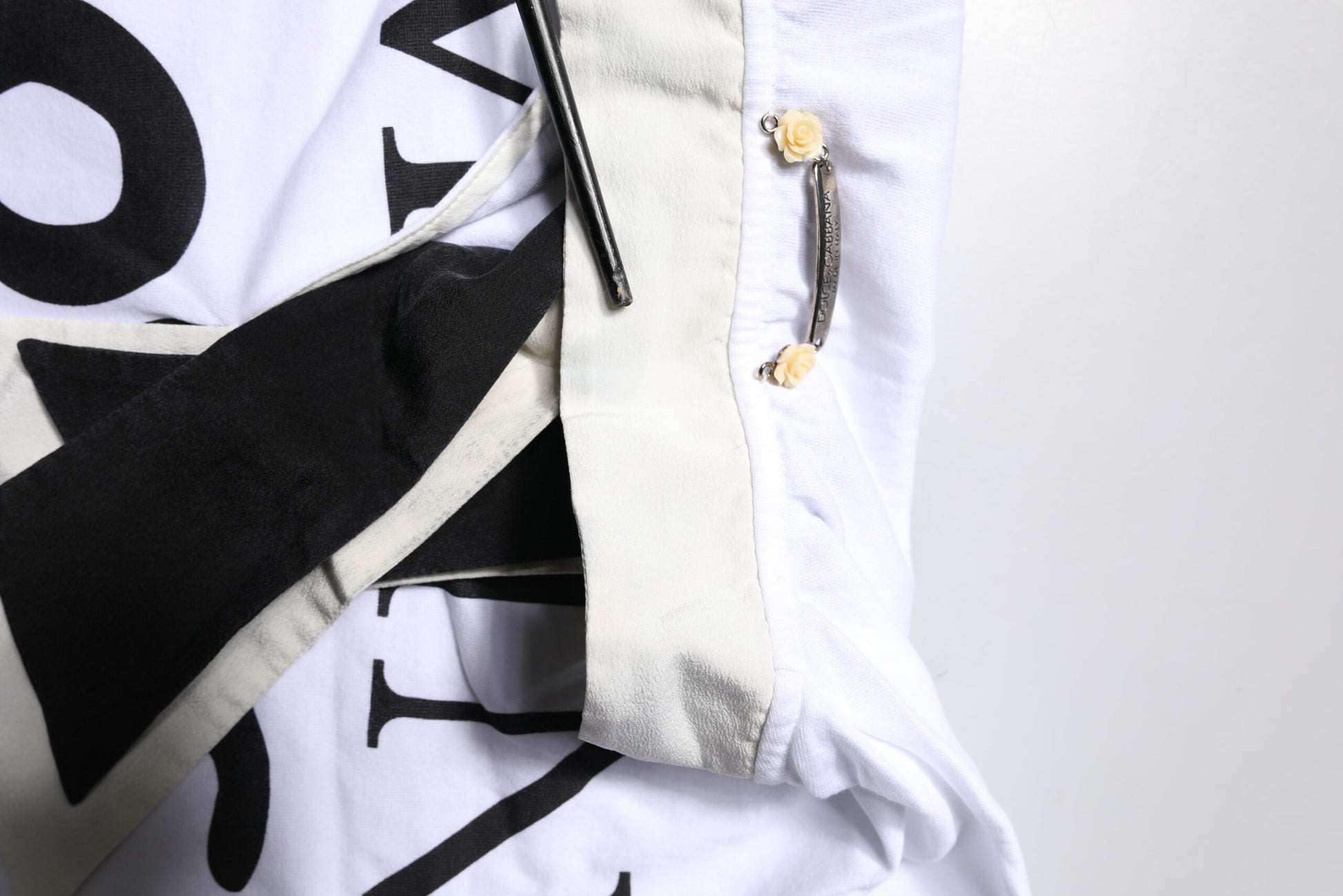 White t-shirt with black lettering and yellow buttons
