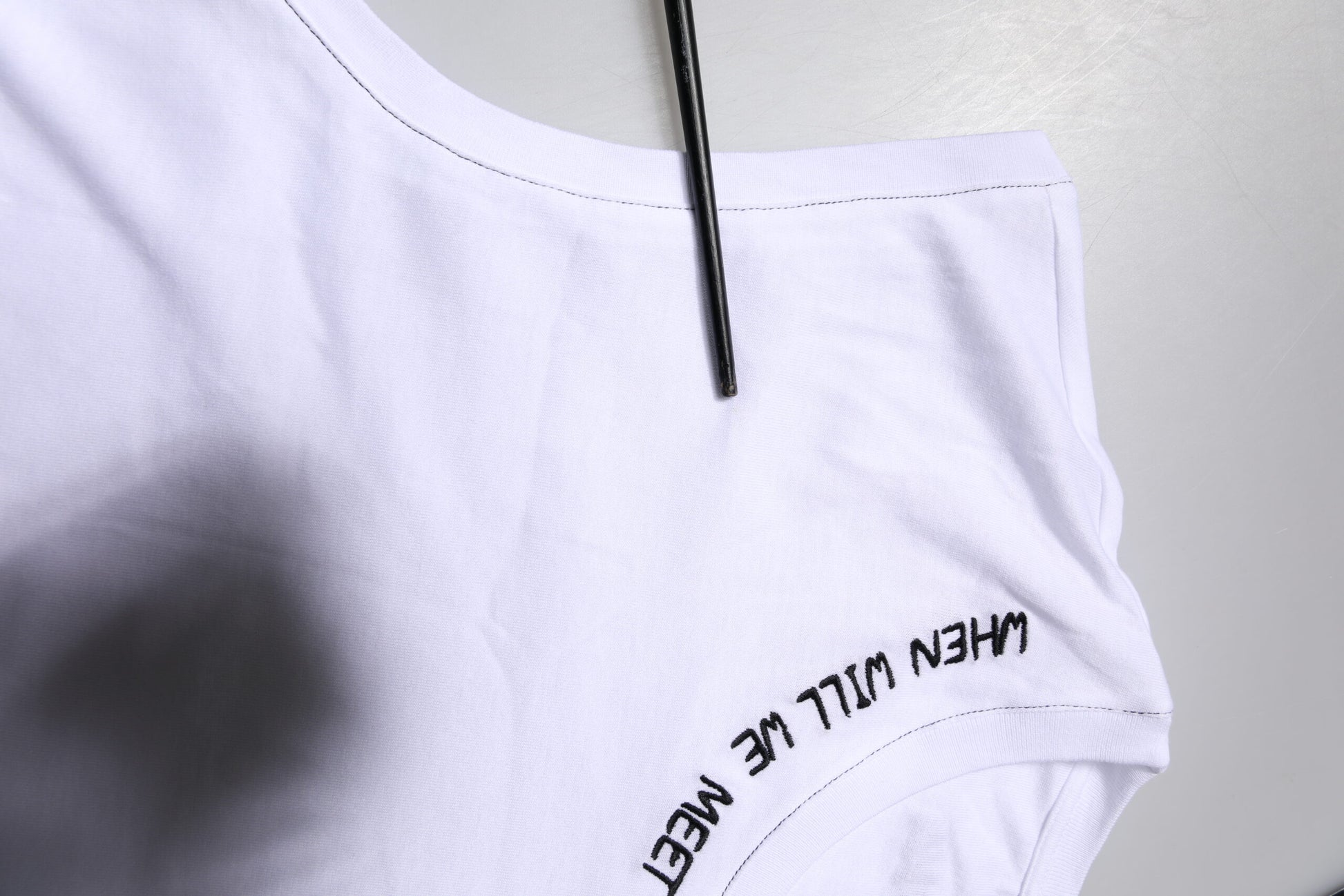 White t-shirt on hanger with black writing