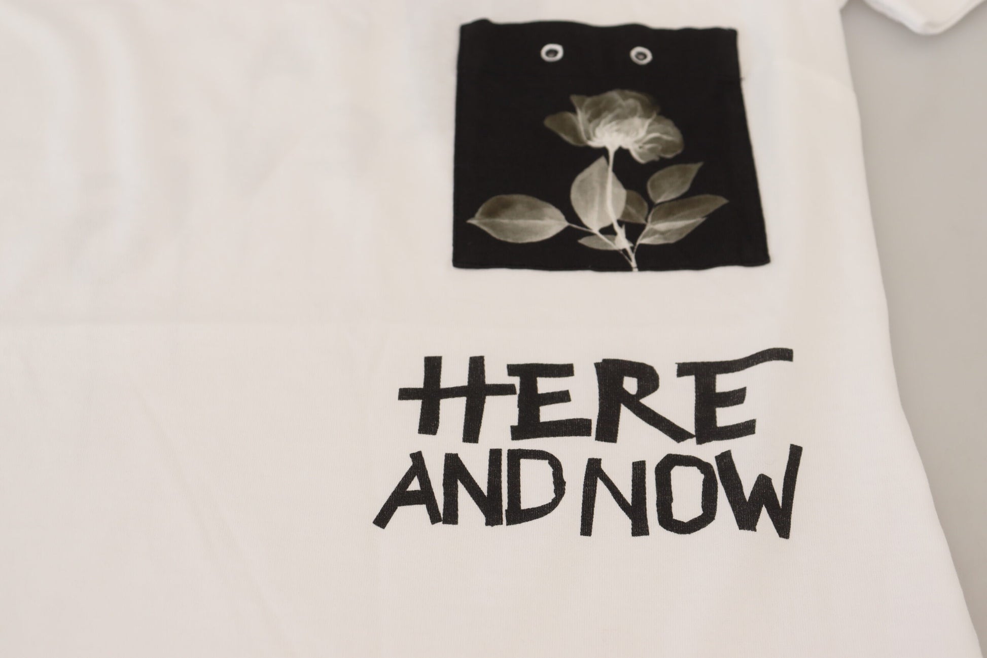 White t-shirt with black design featuring a flower and text