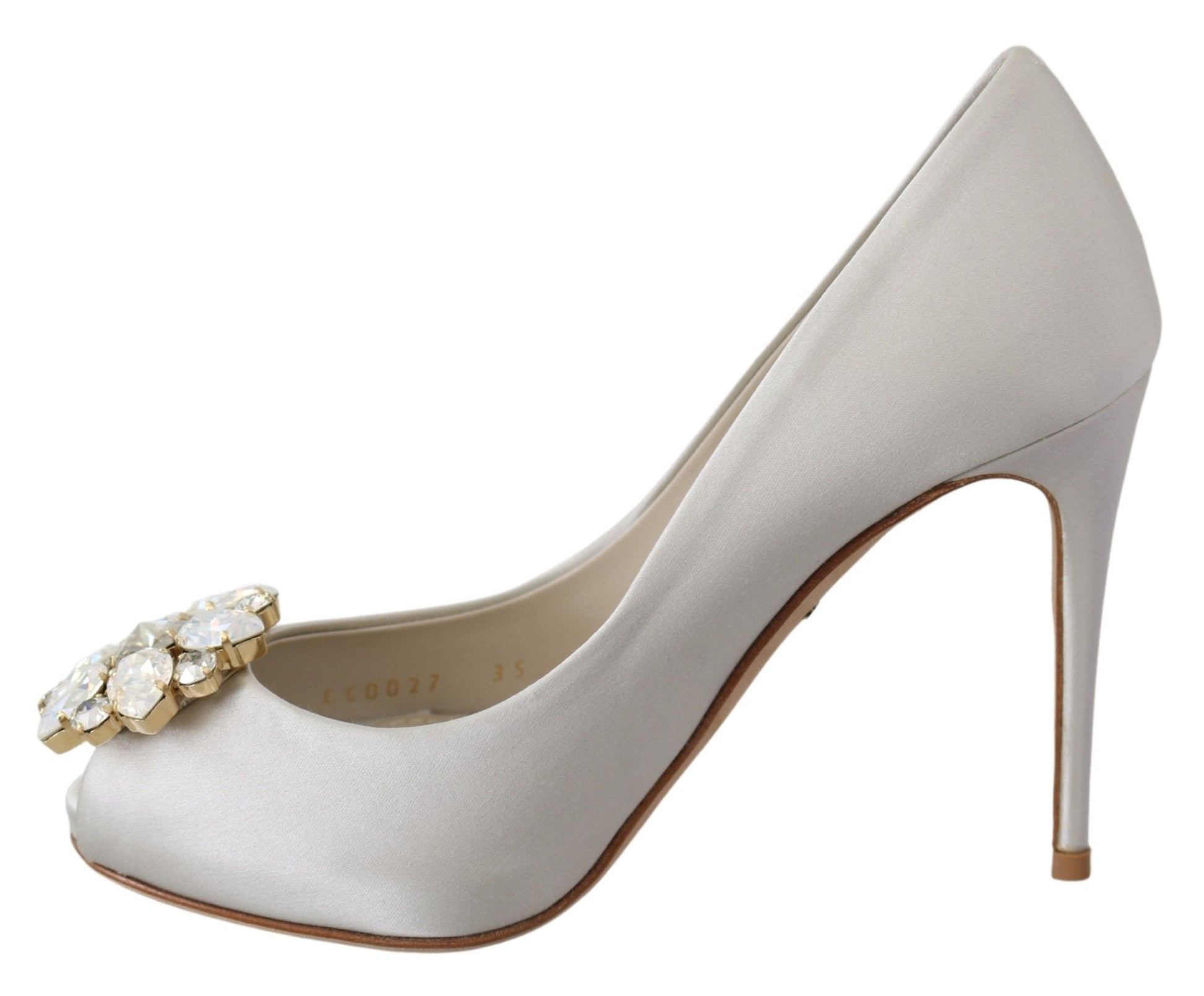 A single high heel shoe with a pointed toe and a stiletto heel. It features a beige or light tan color with a decorative