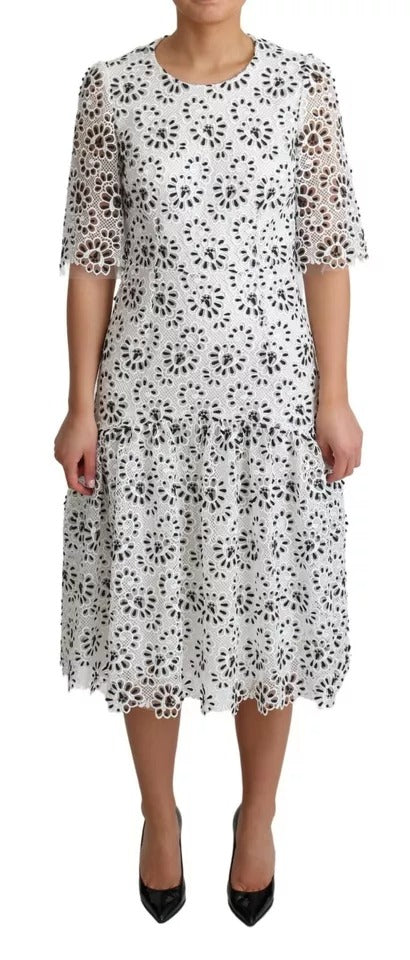 A white midi dress with cutouts and a lace design, made of polyester