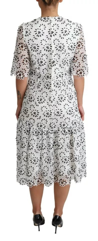 A white midi dress with cutout designs, featuring a polyester fabric and an A-line silhouette