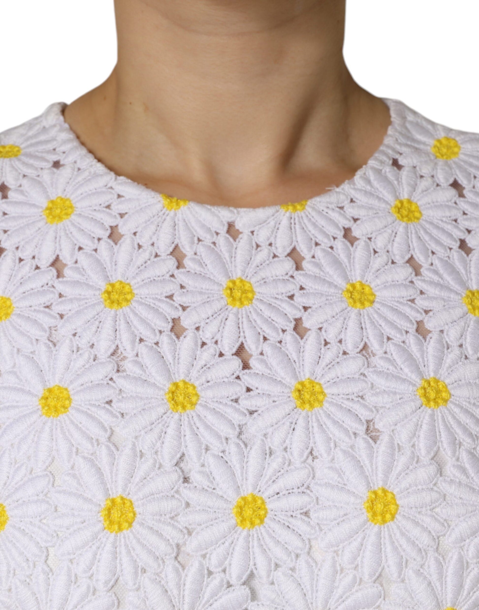 A white midi dress with a macramé lace neckline and yellow daisy embroidery