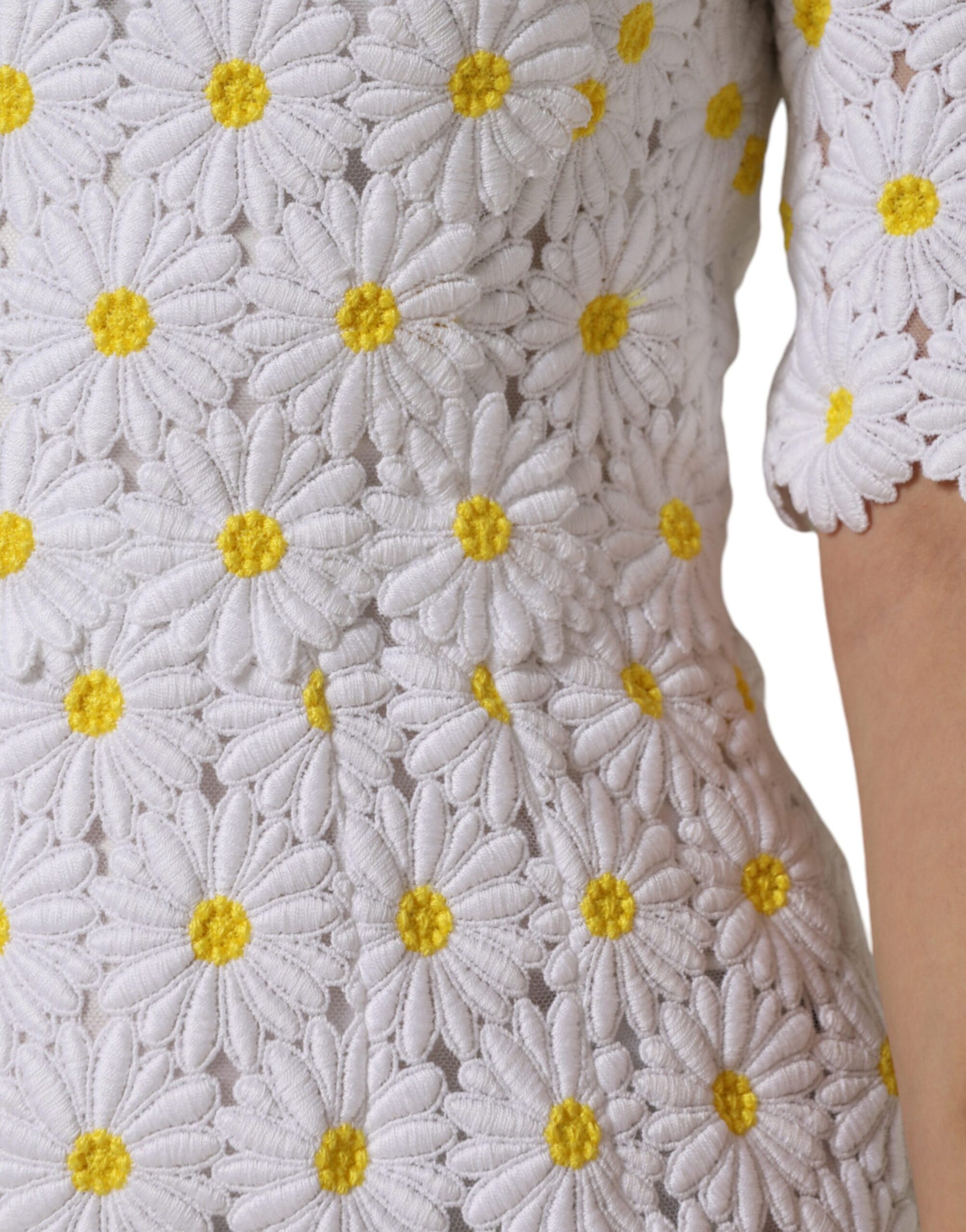 A white midi dress with macramé lace and yellow daisy embroidery