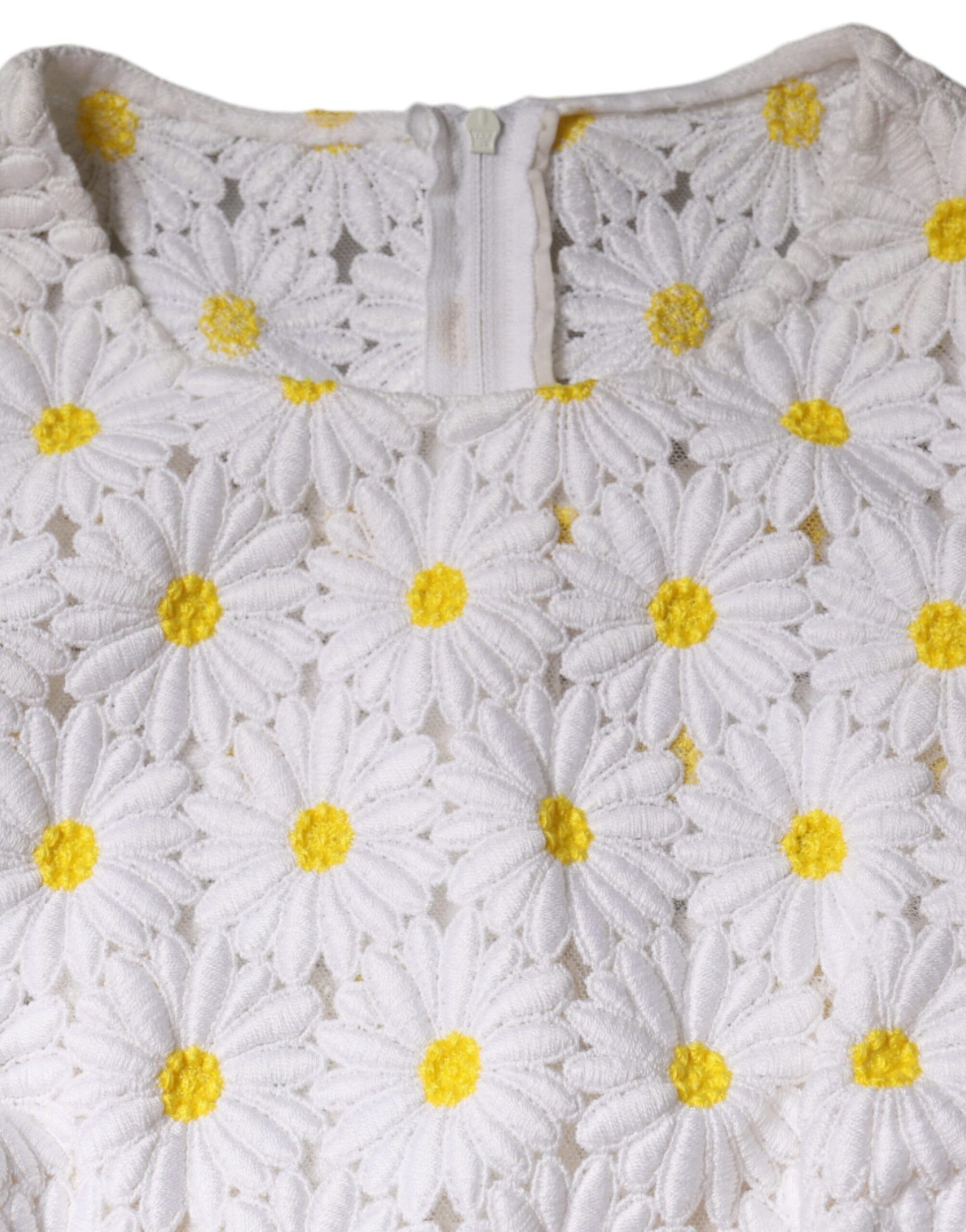 A white midi dress with a macramé lace pattern featuring yellow daisies