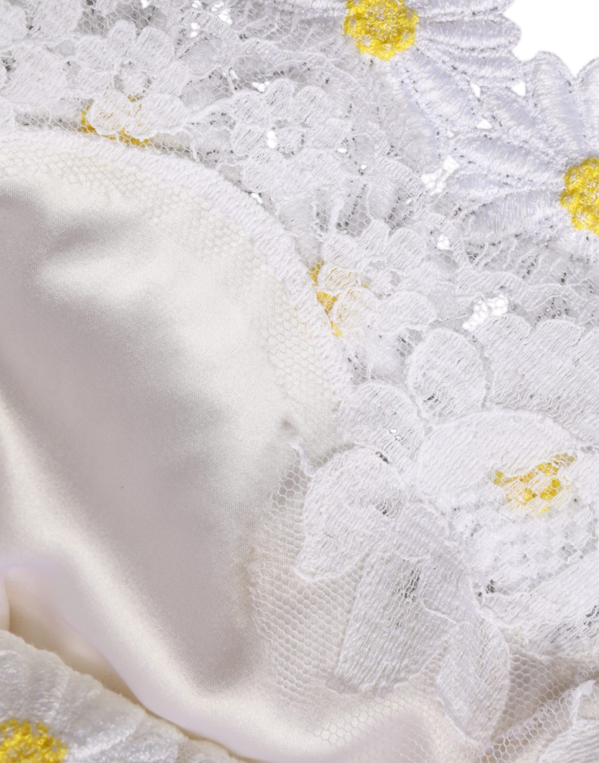 A white lace dress with macramé detailing and yellow daisy embellishments
