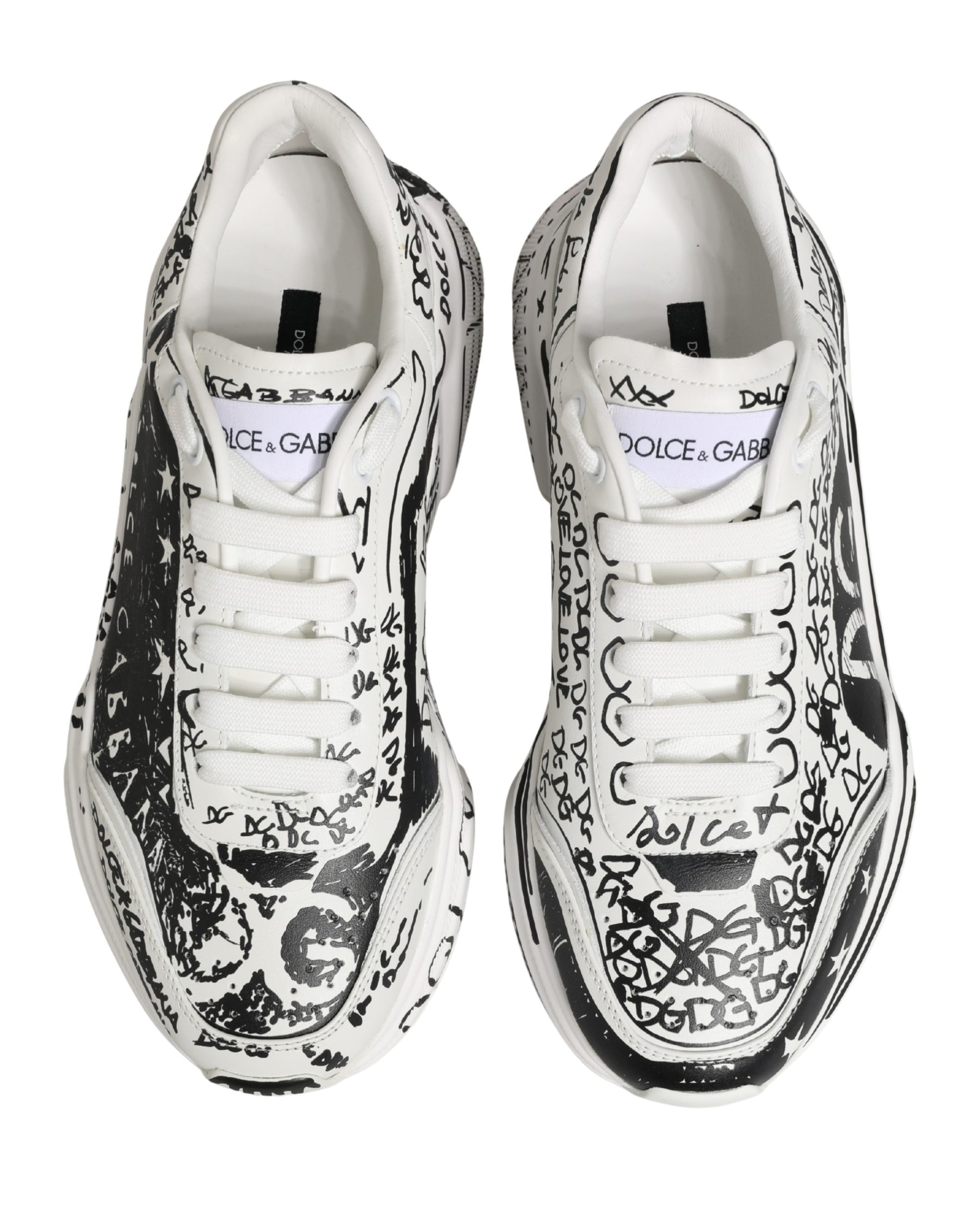 Pair of white sneakers with graffiti-style designs and text, featuring the brand name "Dolce & Gabbana" on side