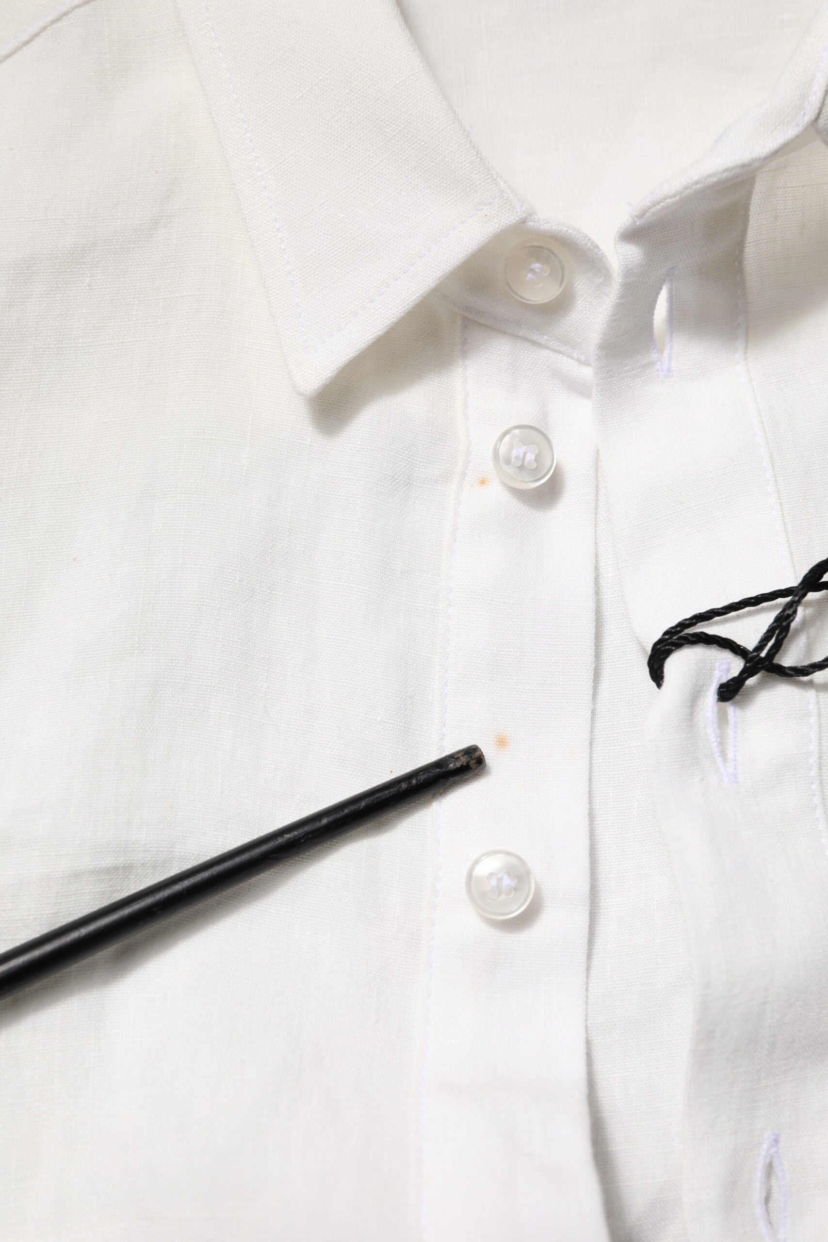White dress shirt with black buttons, embellished with a crown logo on the left chest