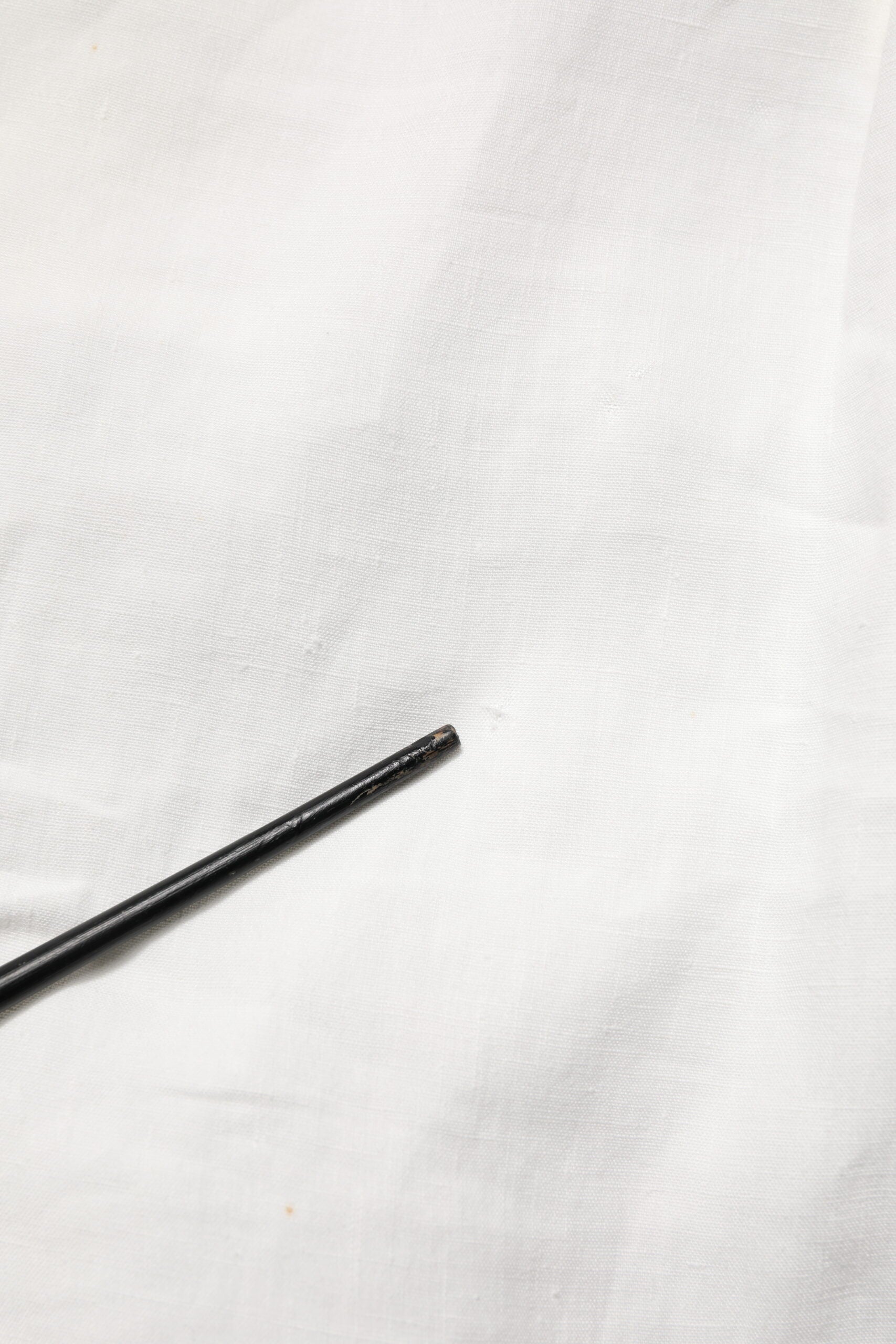 Black dress pin on white fabric