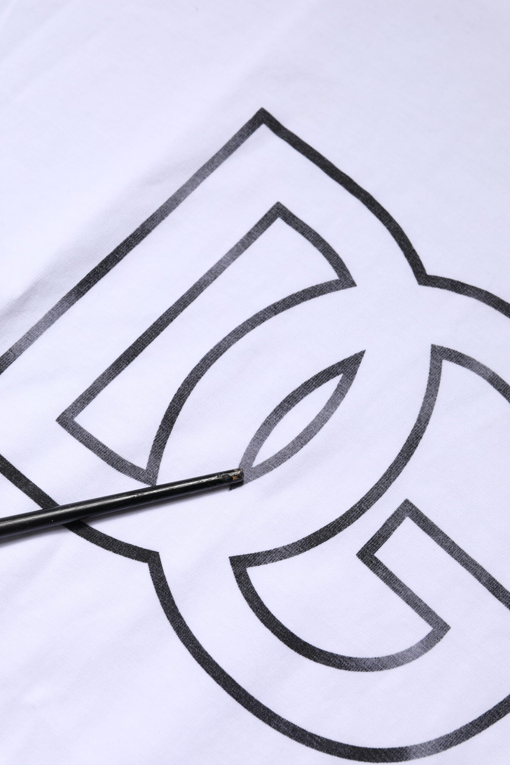 Hand holding a pen over a white surface with a logo drawn on it